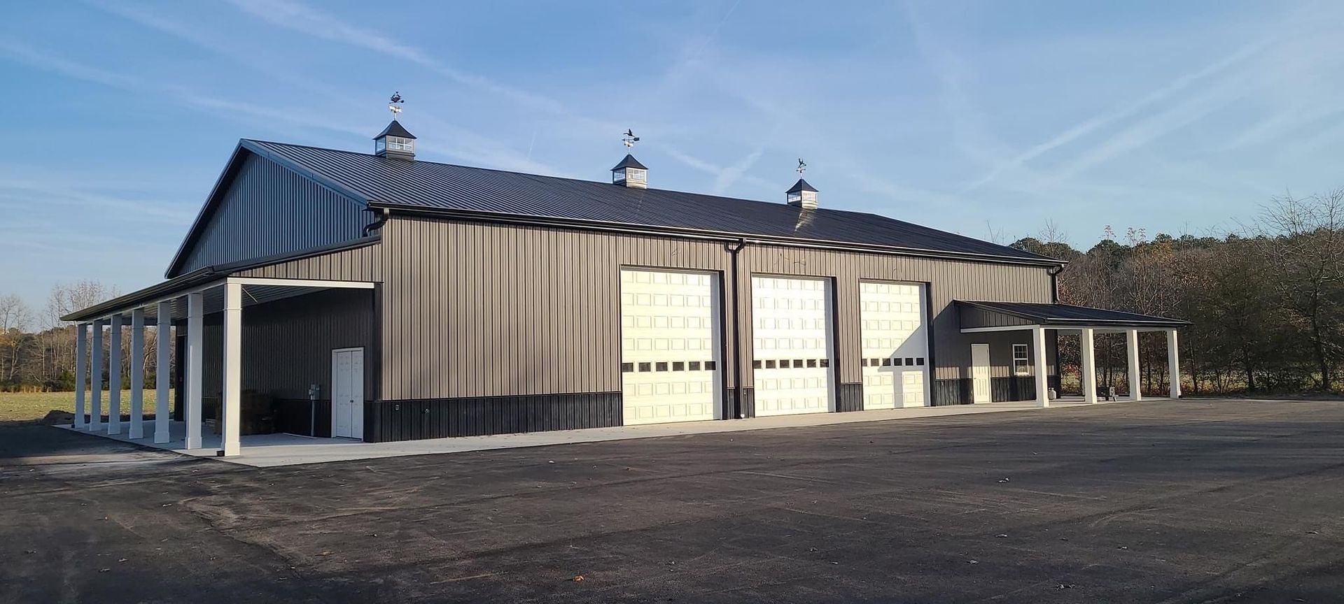 A large barn with a lot of doors is sitting on top of a dirt field.