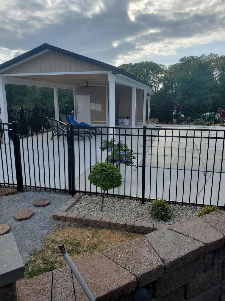 A house with a fence around it and a pool behind it.