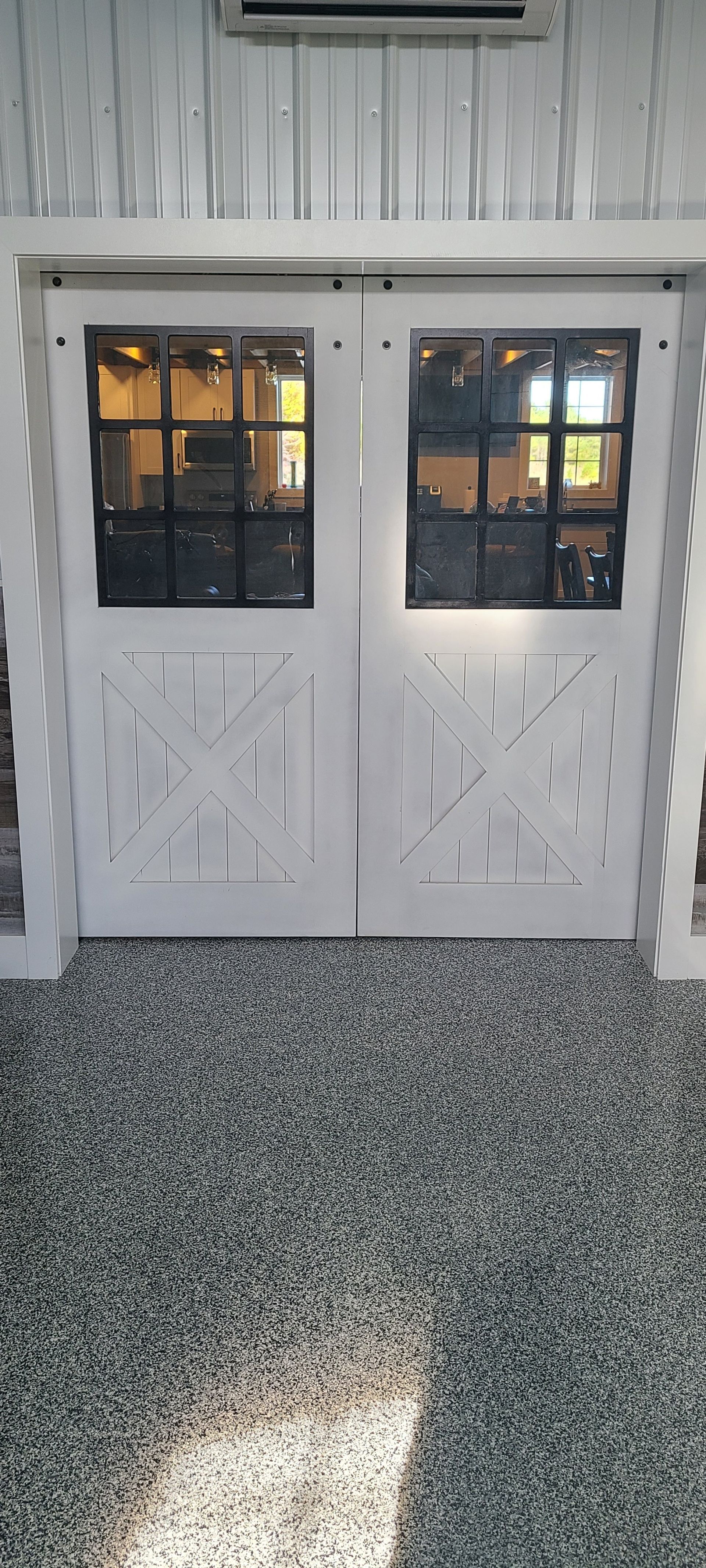 A pair of white doors with black windows in a room.