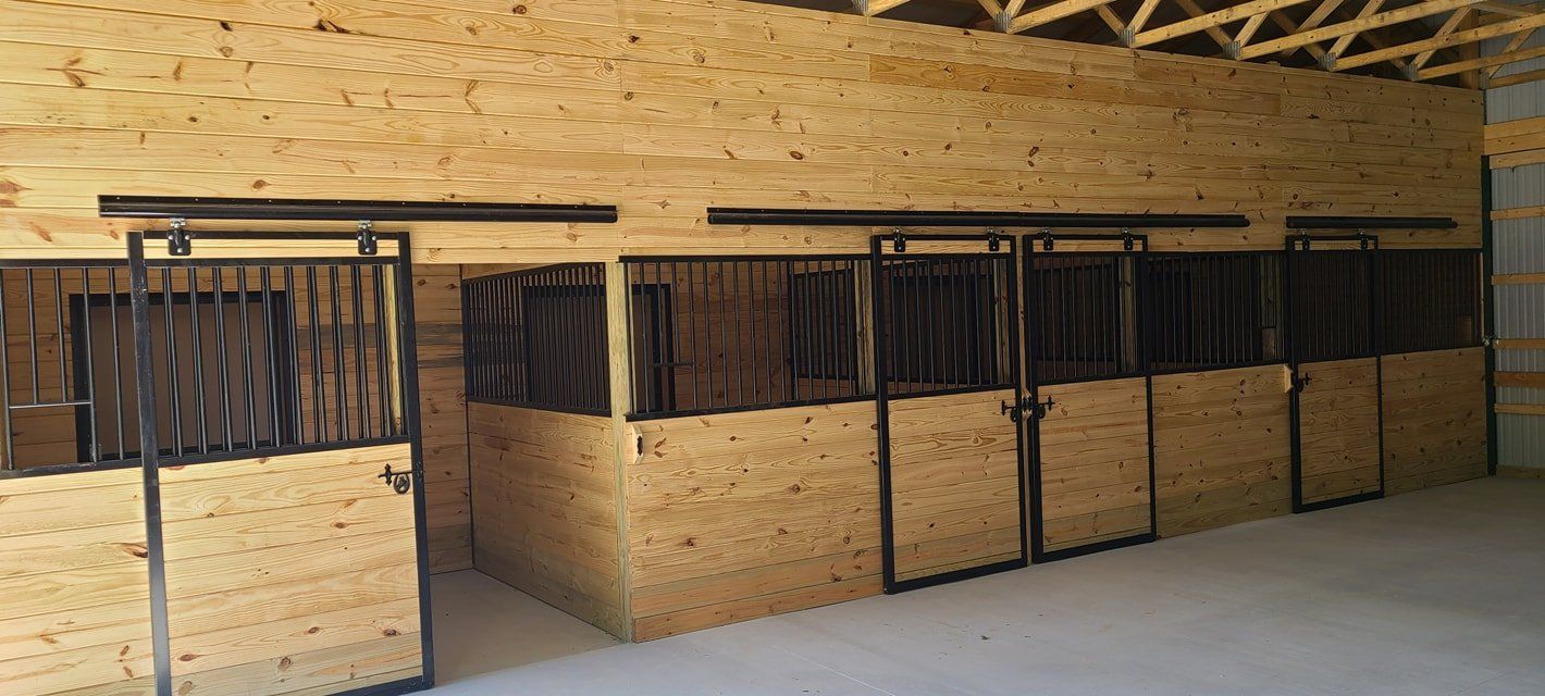 A row of wooden horse stalls in a barn.