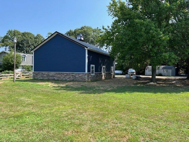 A blue barn is sitting in the middle of a lush green field.