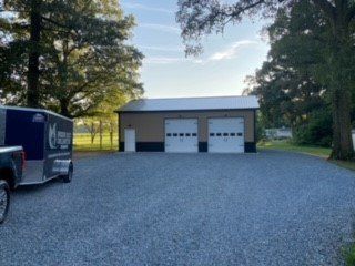 A truck and trailer are parked in front of a garage.