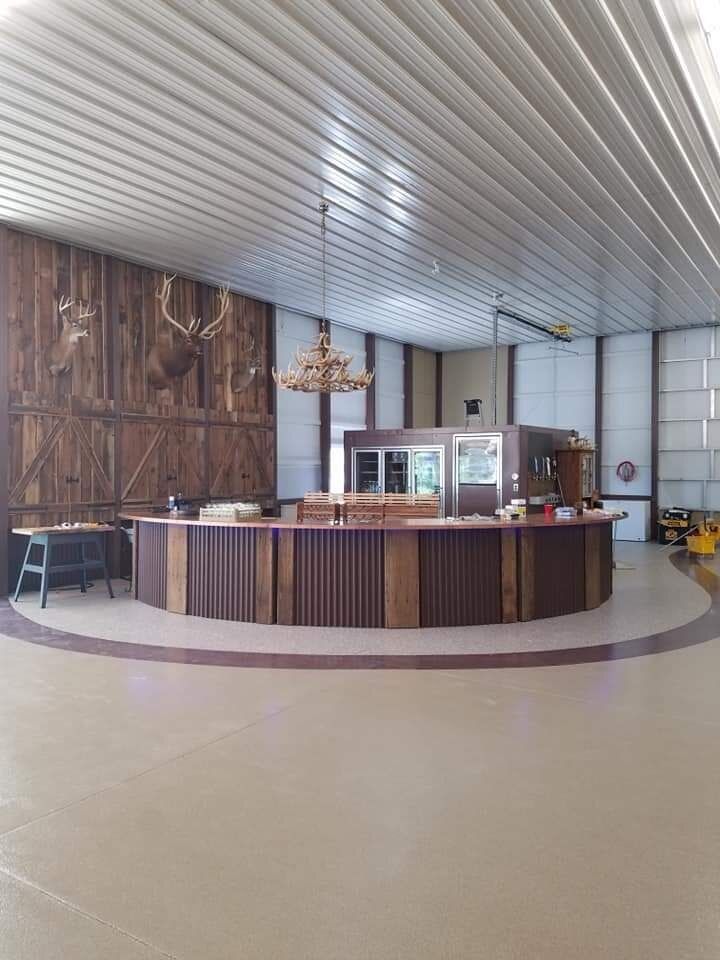 A large room with a bar and a deer head on the wall.