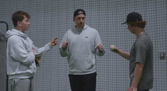 A group of young men are standing next to each other in front of a baseball net.
