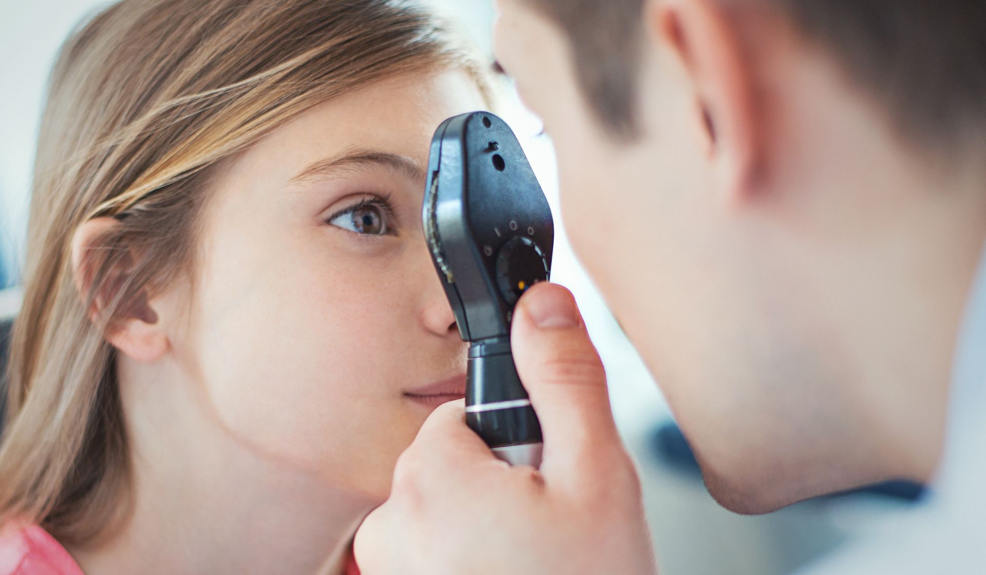 Closeup of optician checking female patient eyesight, showcasing professional eye care services.