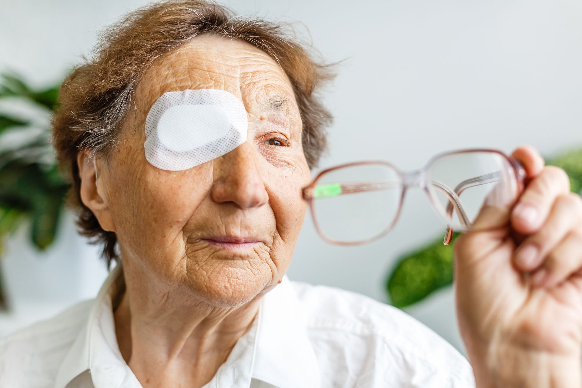 An elderly woman uses a white eye patch after an eye surgery