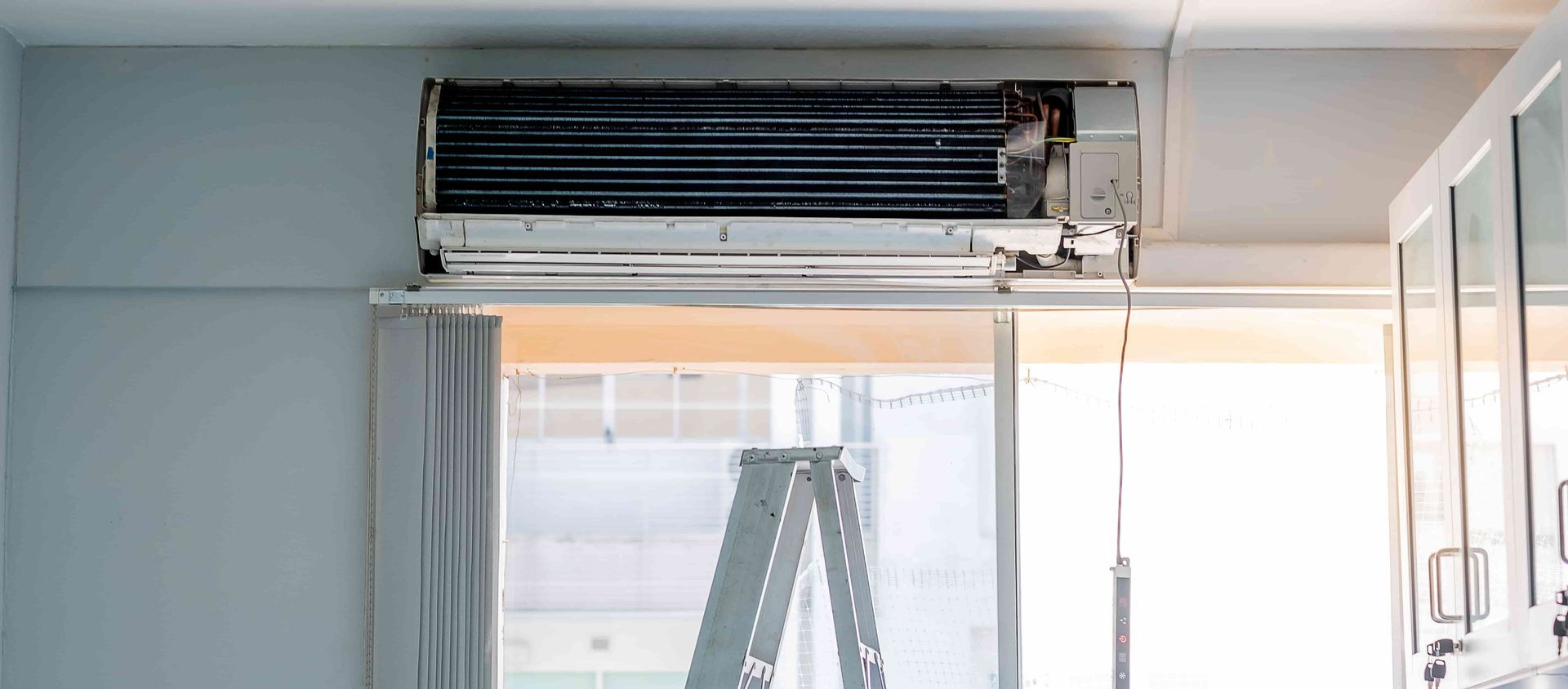 An air conditioner is being installed in a room next to a window.