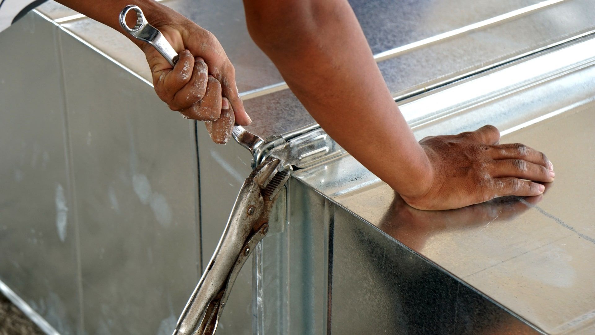 A person is cutting a piece of metal with a pair of pliers.