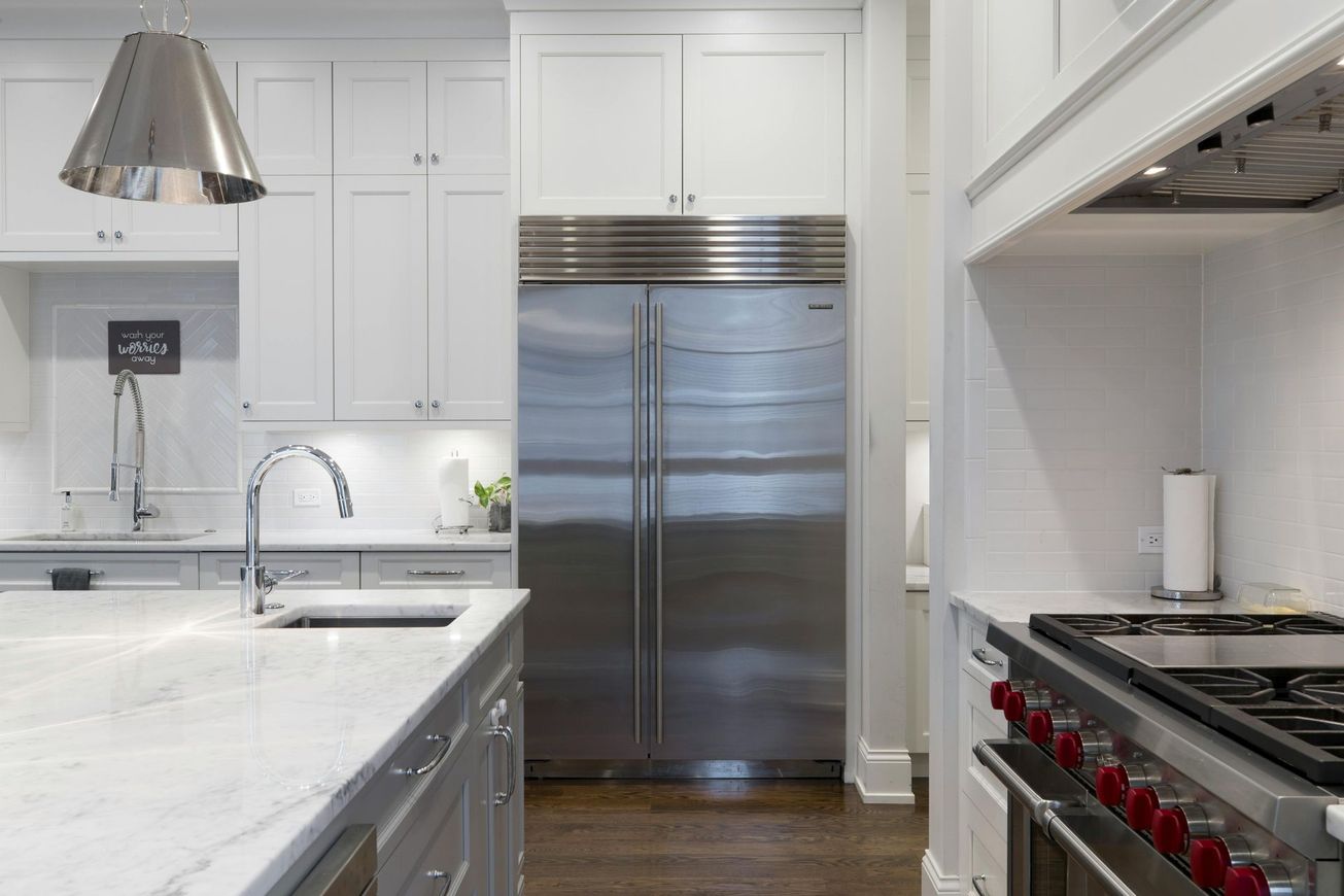 A kitchen with stainless steel appliances and white cabinets.