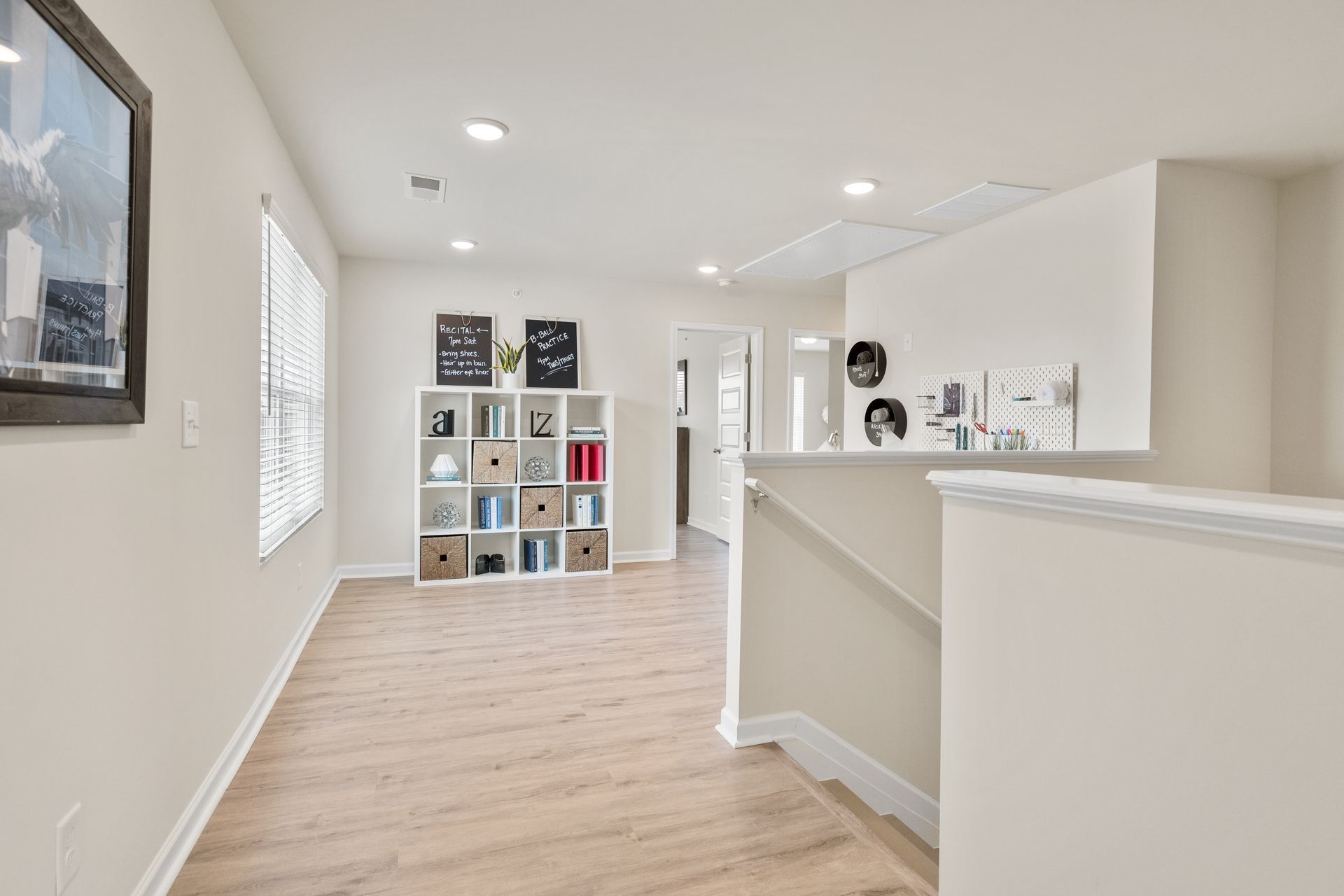 A hallway leading to a living room with a shelf and stairs.