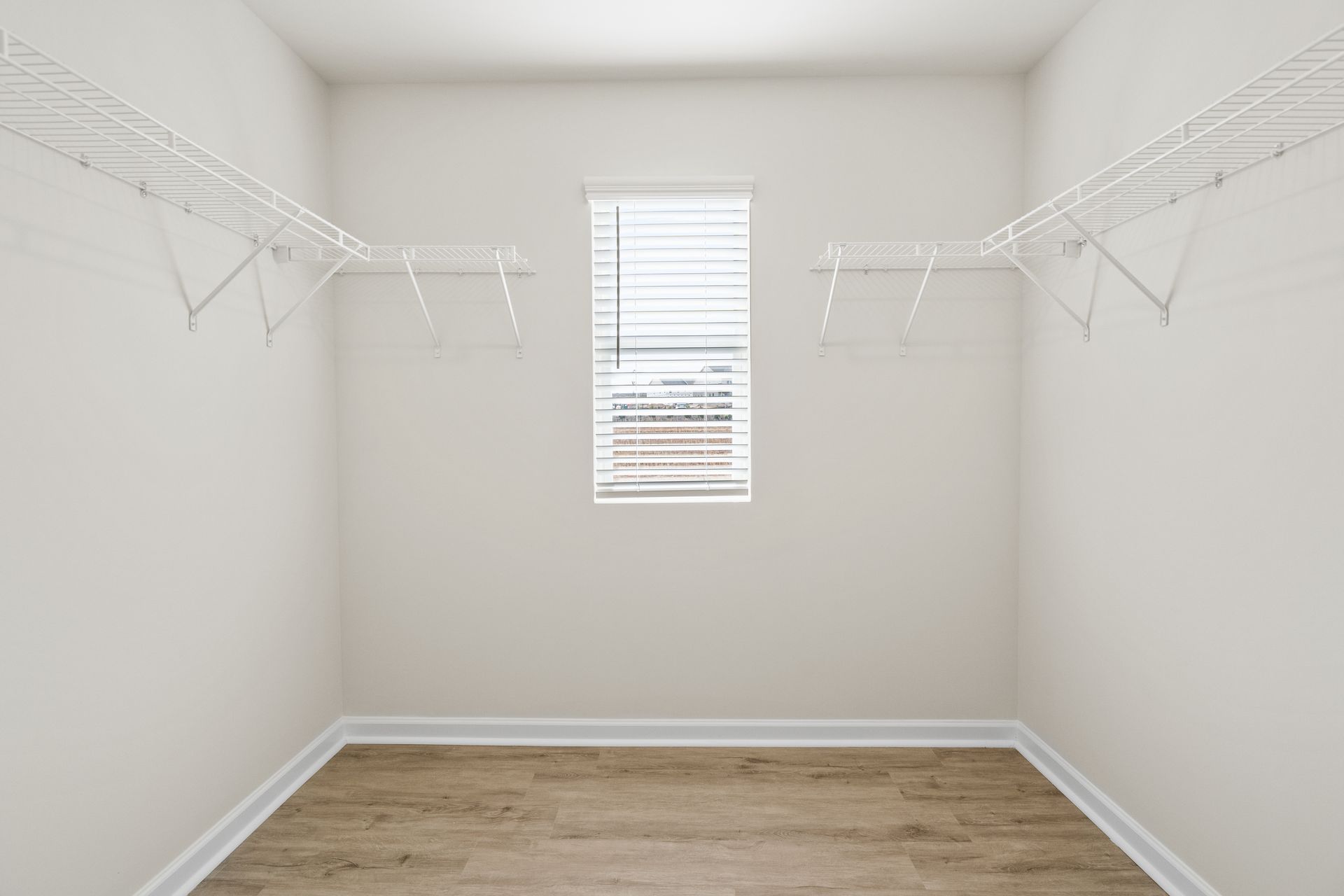 An empty walk in closet with a window and shelves.