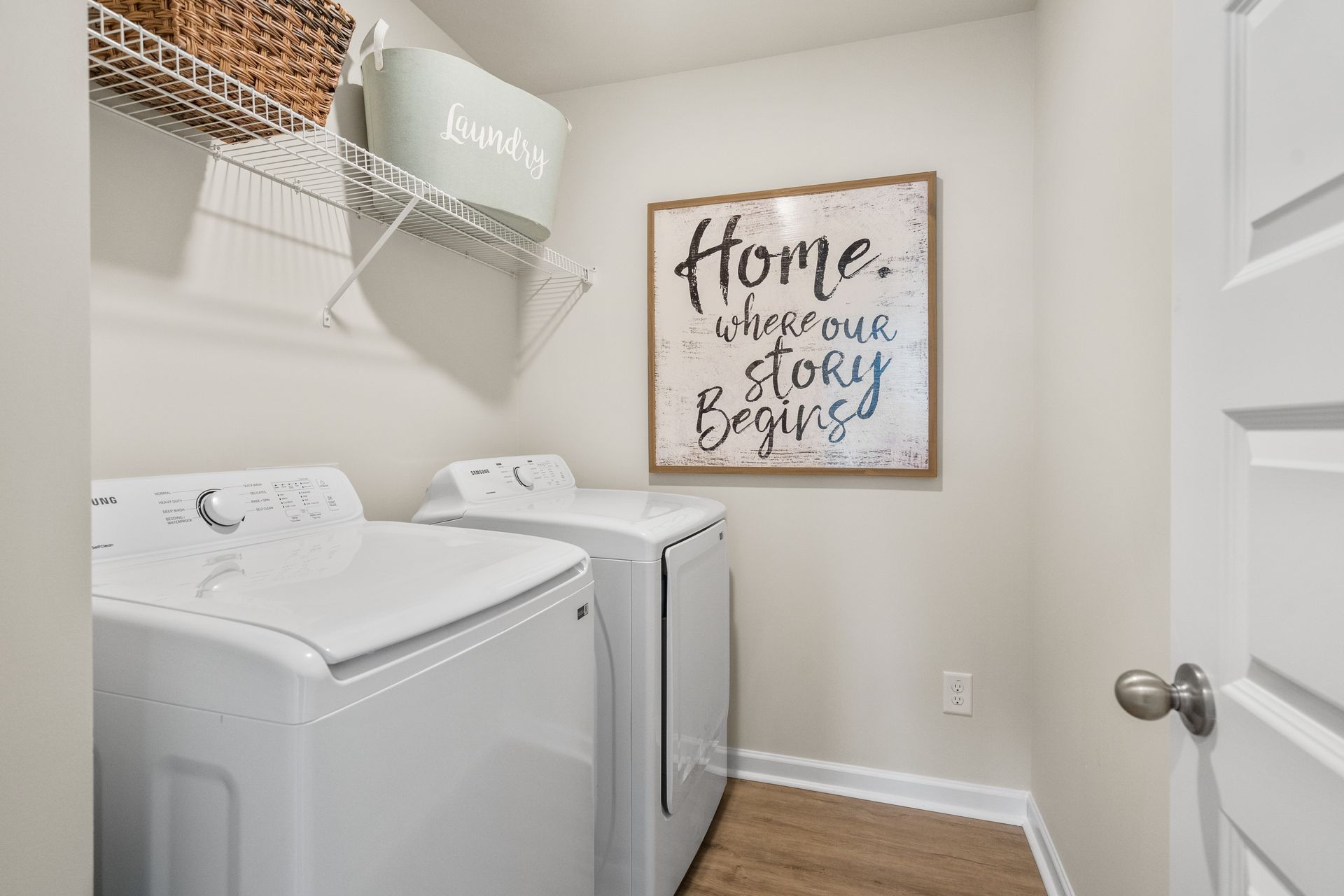 A laundry room with a washer and dryer and a sign on the wall.