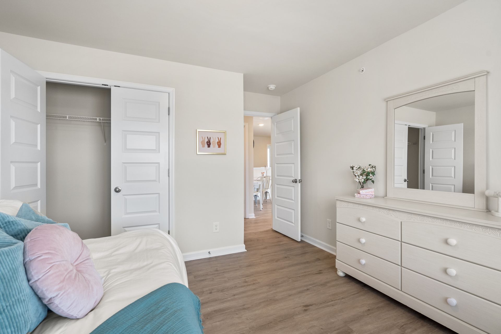 A bedroom with a bed , dresser , mirror and closet.