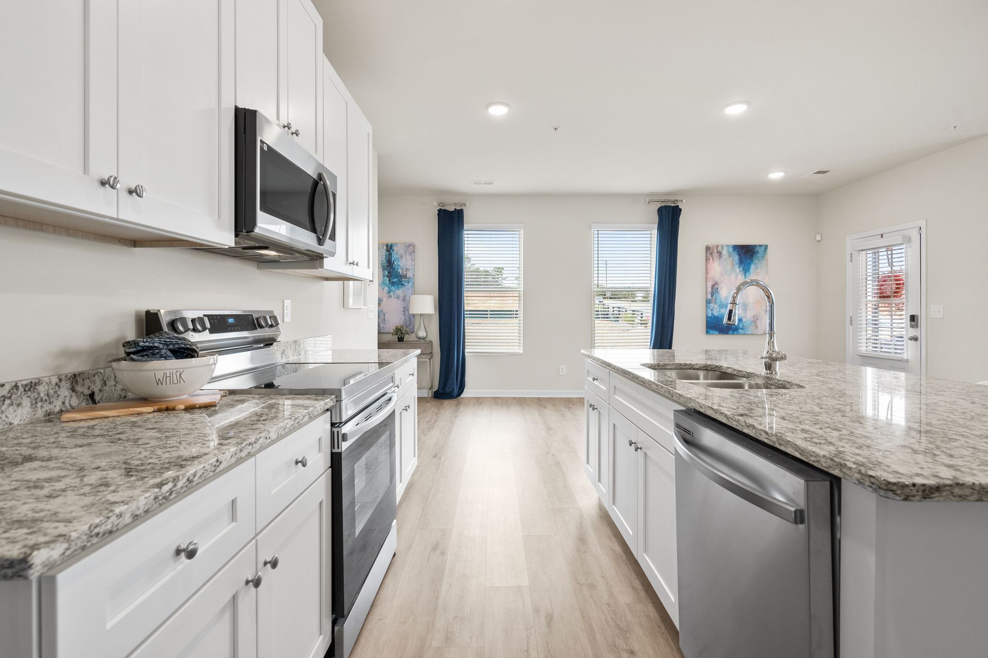 A kitchen with granite counter tops , stainless steel appliances , and white cabinets.