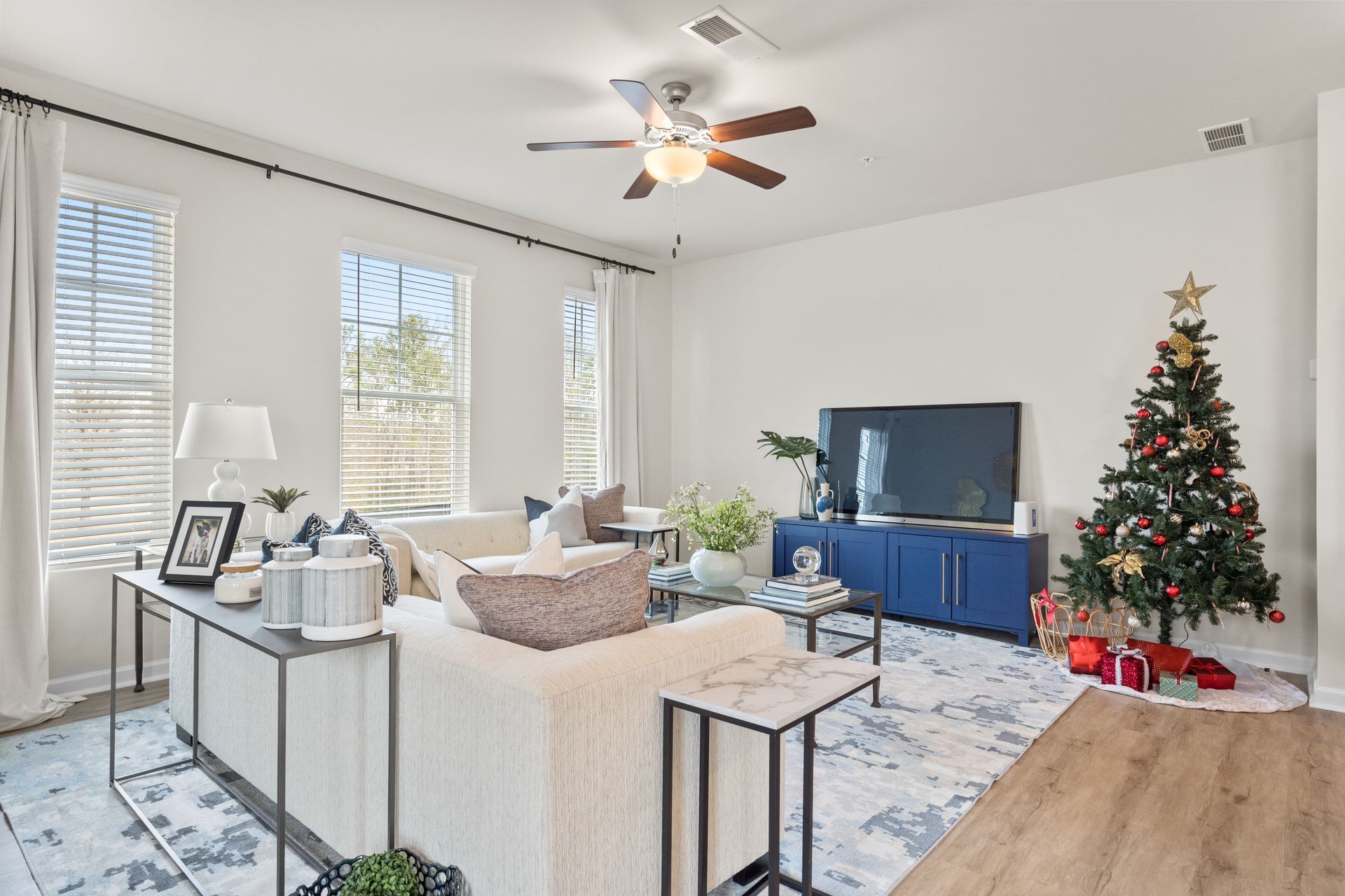 A living room with a christmas tree and a ceiling fan.