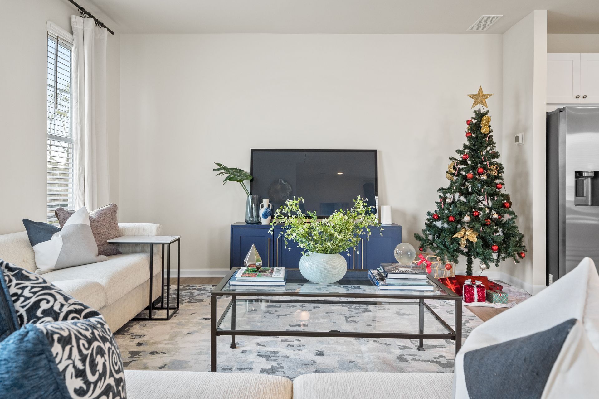 A living room with a christmas tree and a flat screen tv.