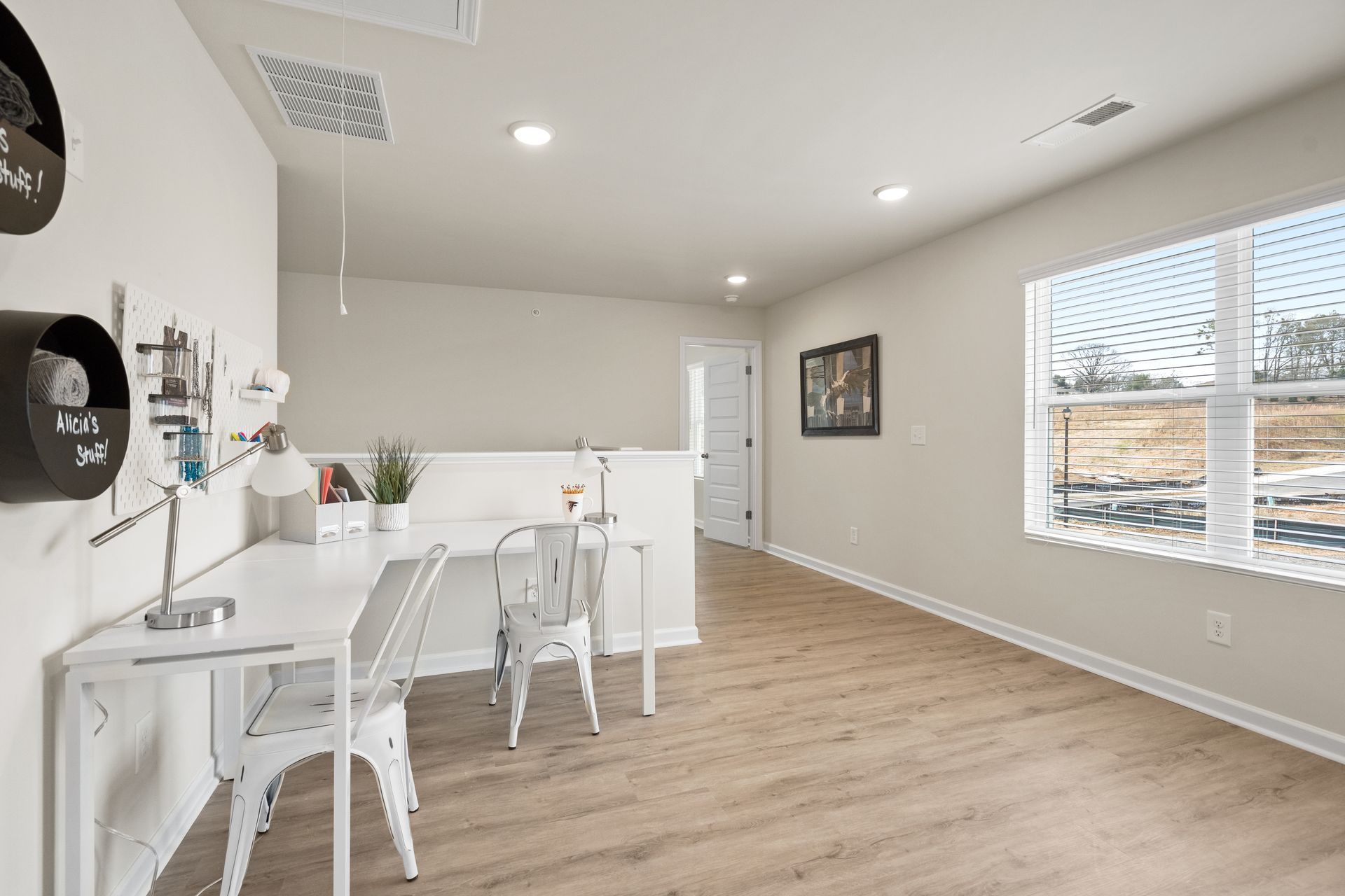 A room with a desk and chairs in it and a window.