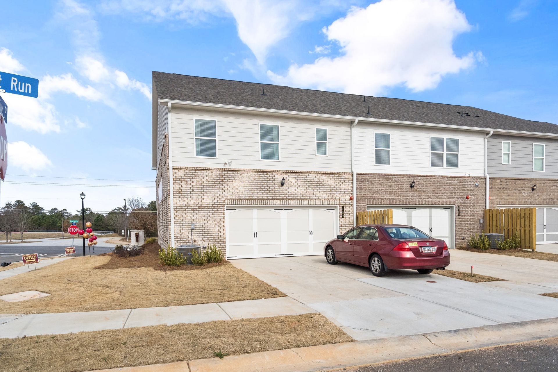 A red car is parked in front of a row of houses.