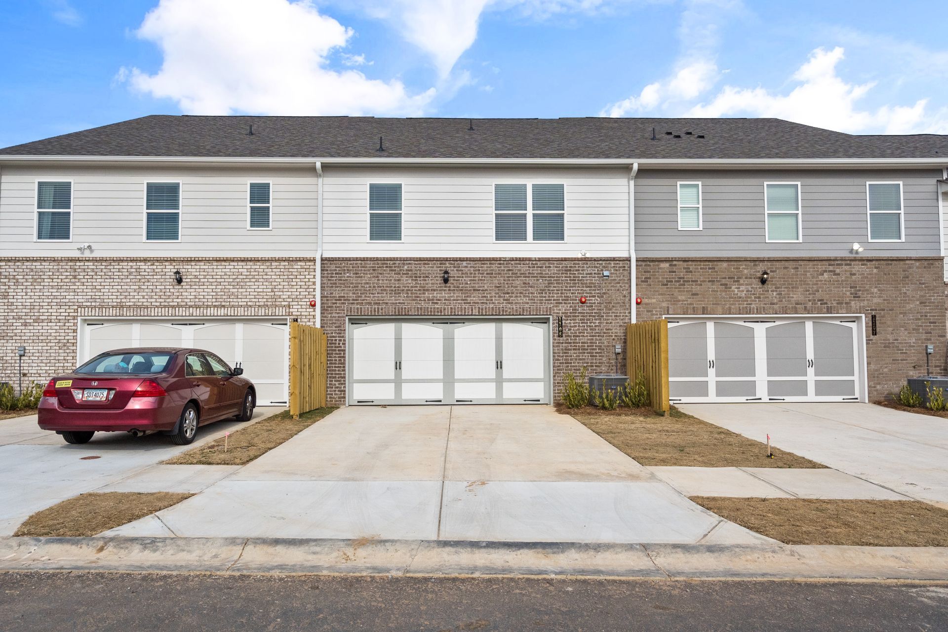 A red car is parked in front of a row of houses