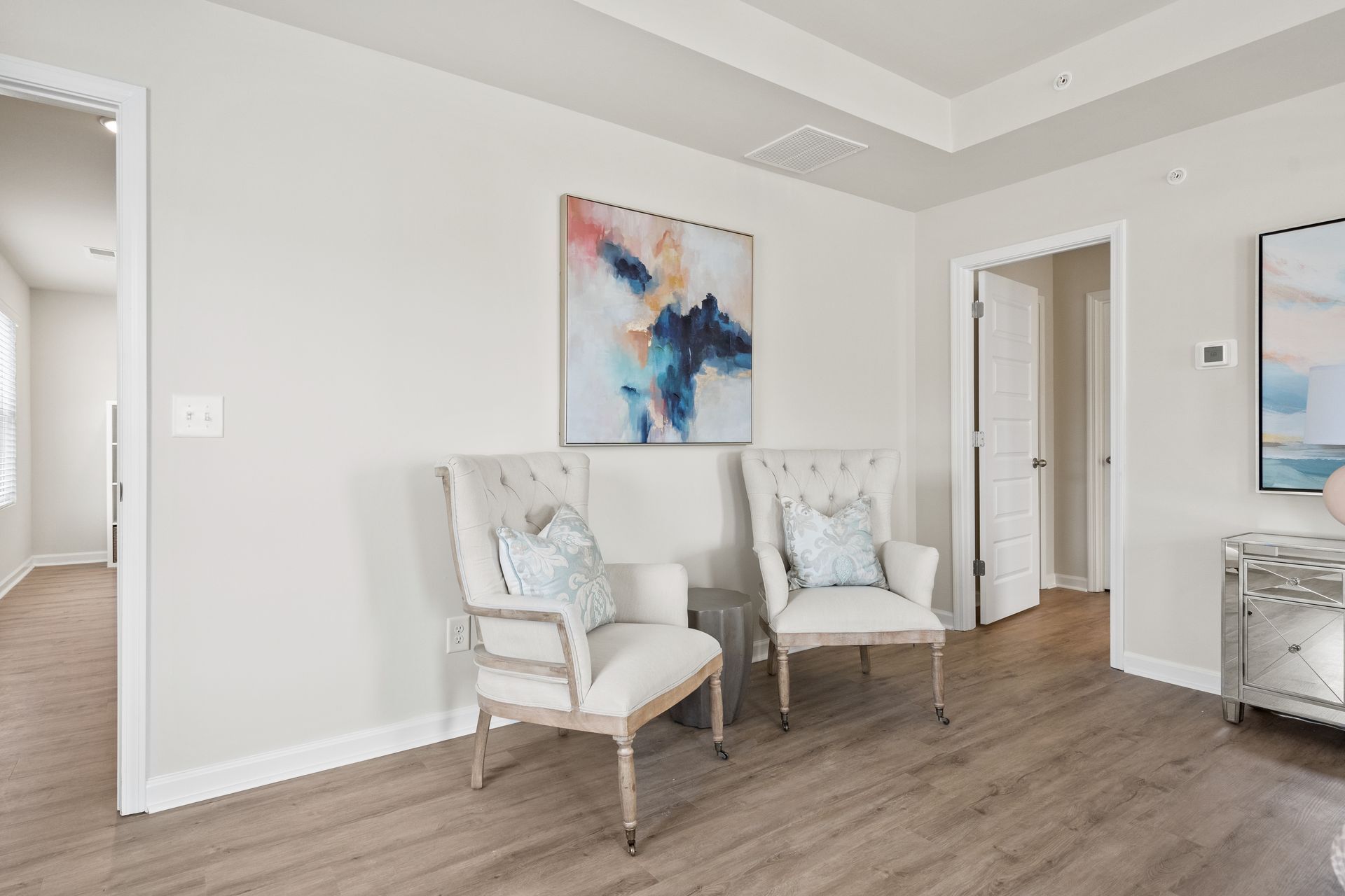 A living room with two chairs and a painting on the wall.