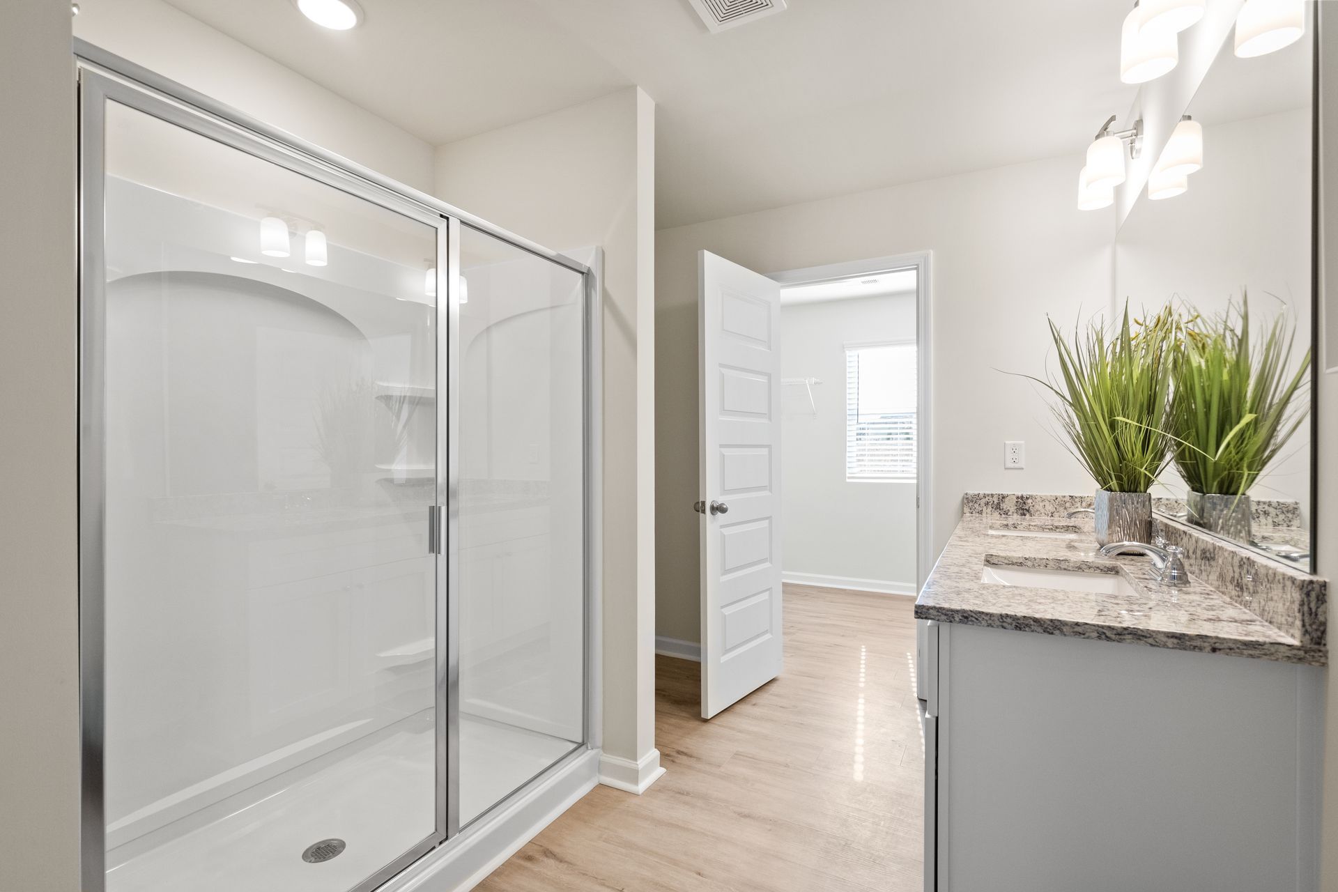 A bathroom with a walk in shower , sink and mirror.