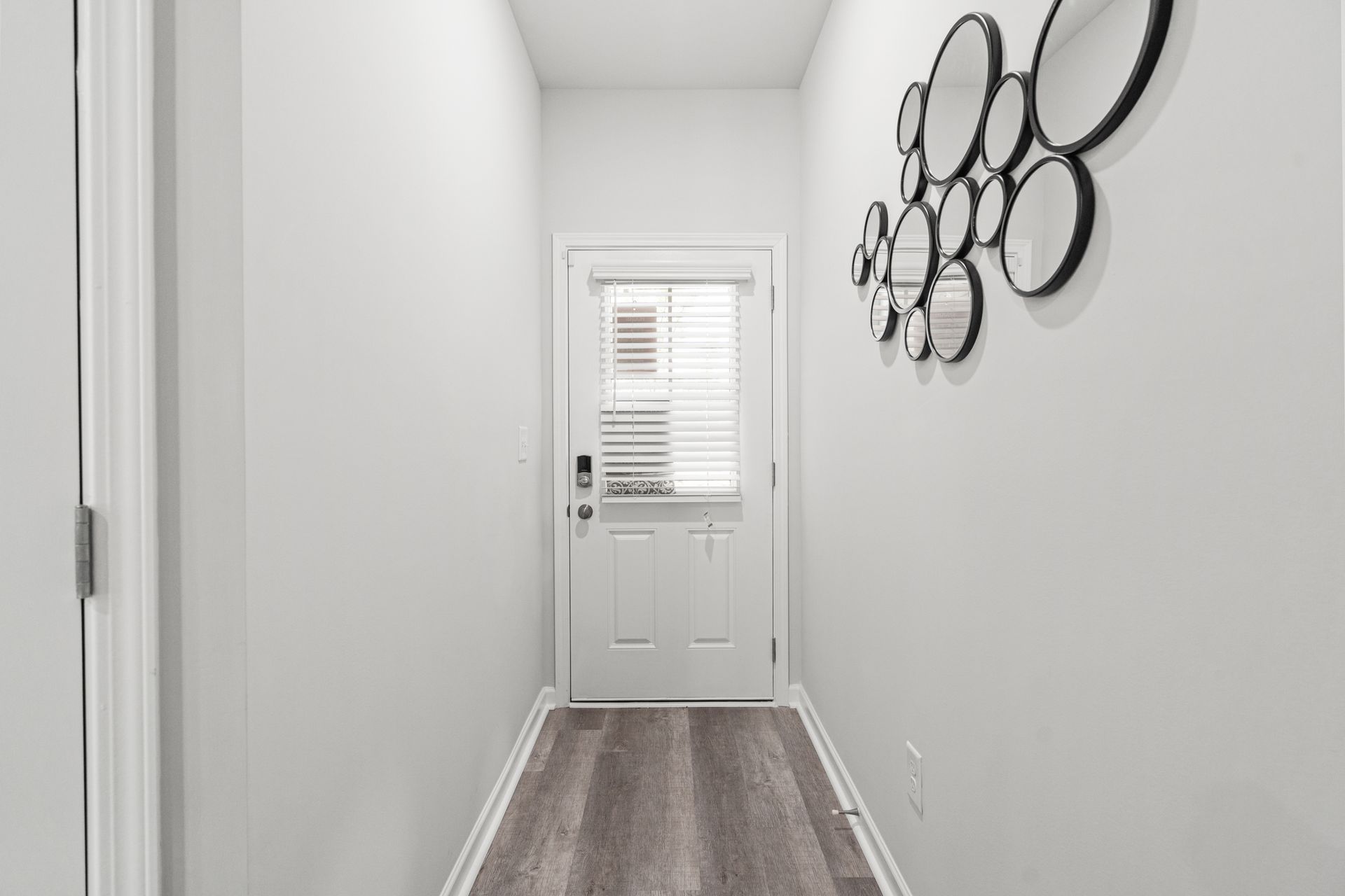 A hallway with a white door and a wooden floor.