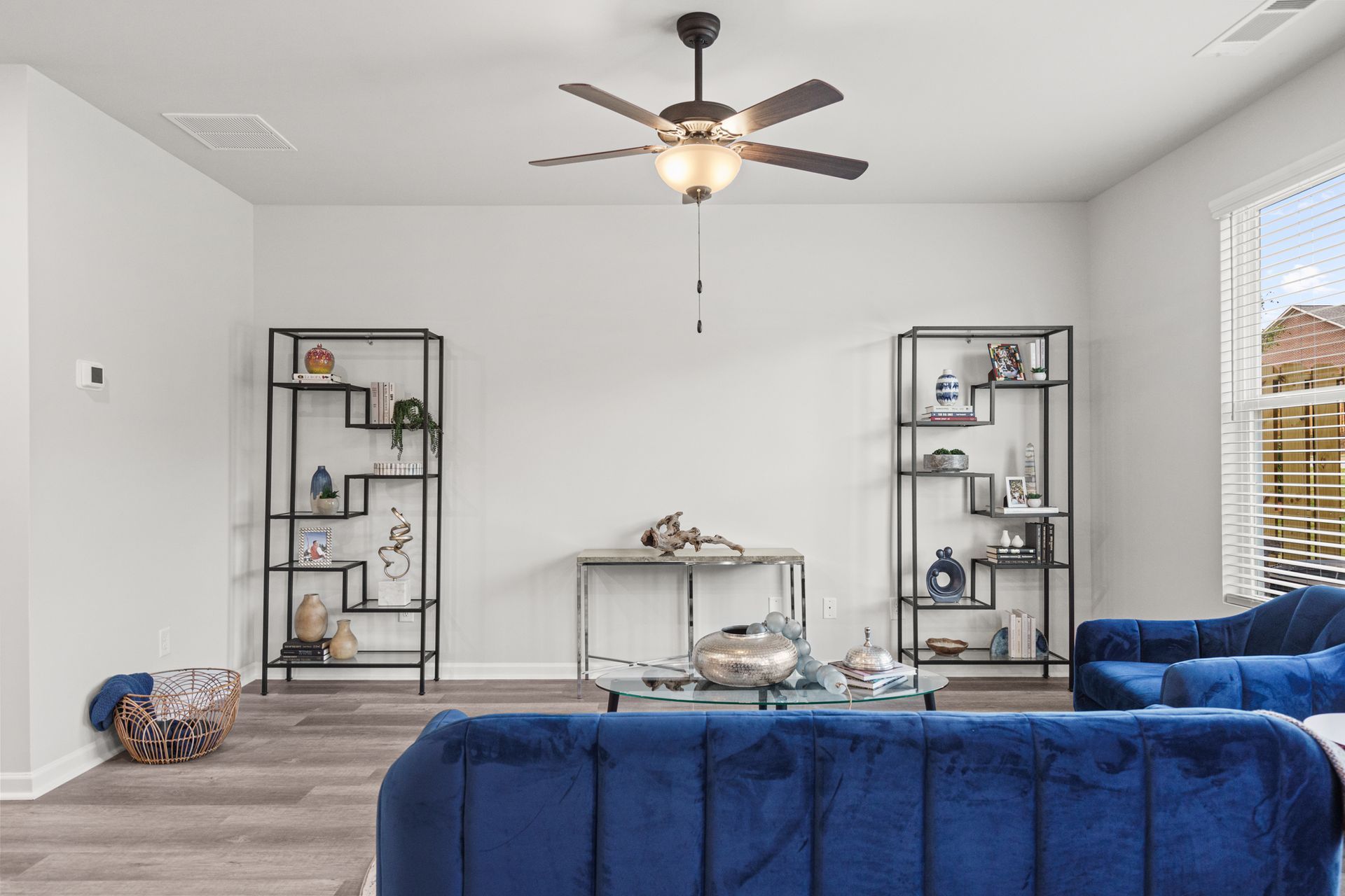 A living room with a blue couch and a ceiling fan.