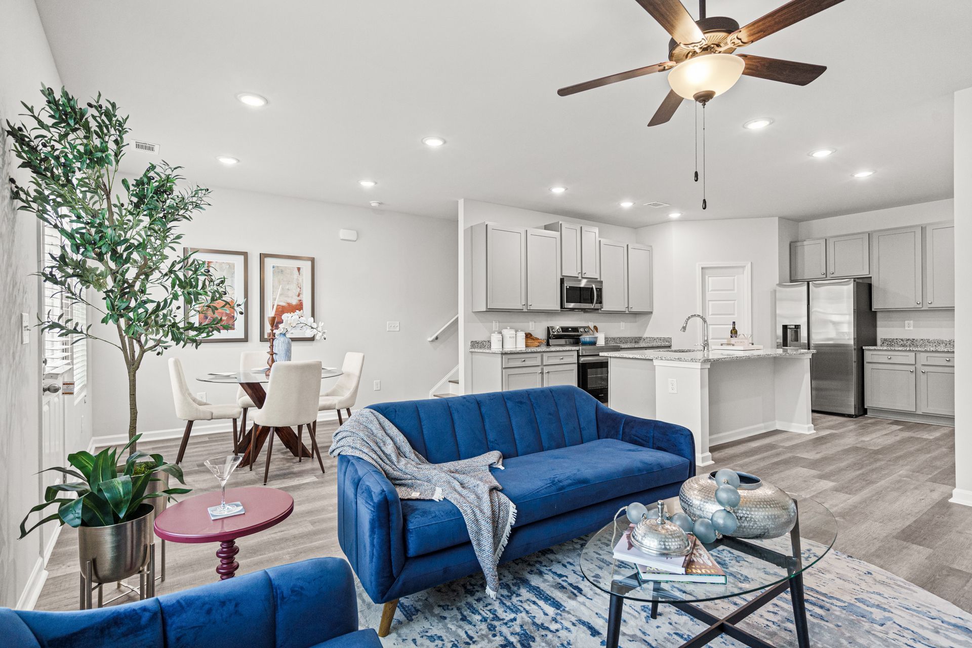 A living room with a blue couch and a ceiling fan.