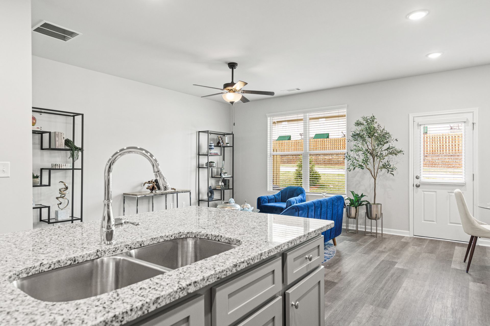 A kitchen with a double sink , granite counter tops , and a ceiling fan.