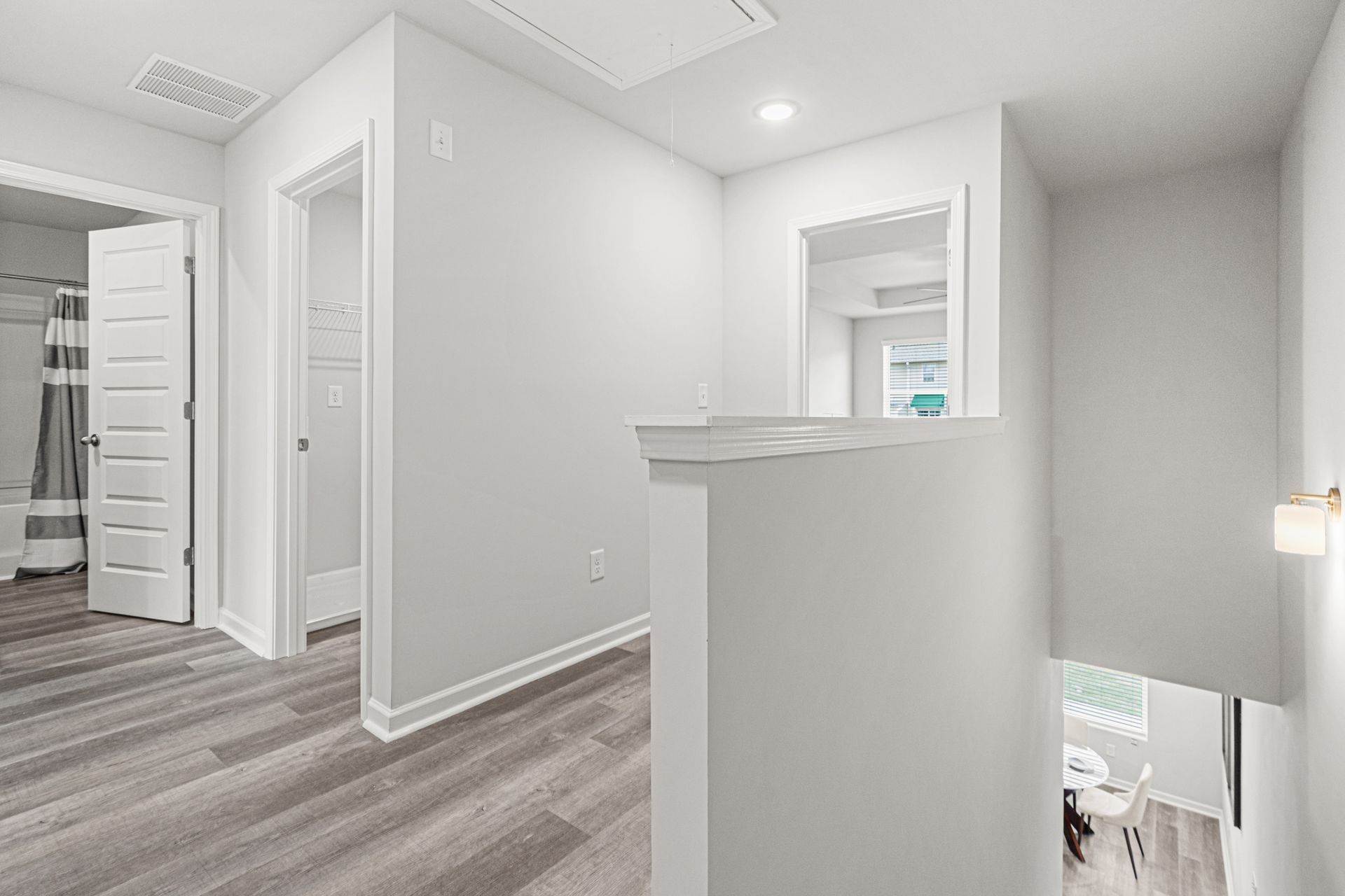 A hallway with hardwood floors and white walls in a house.