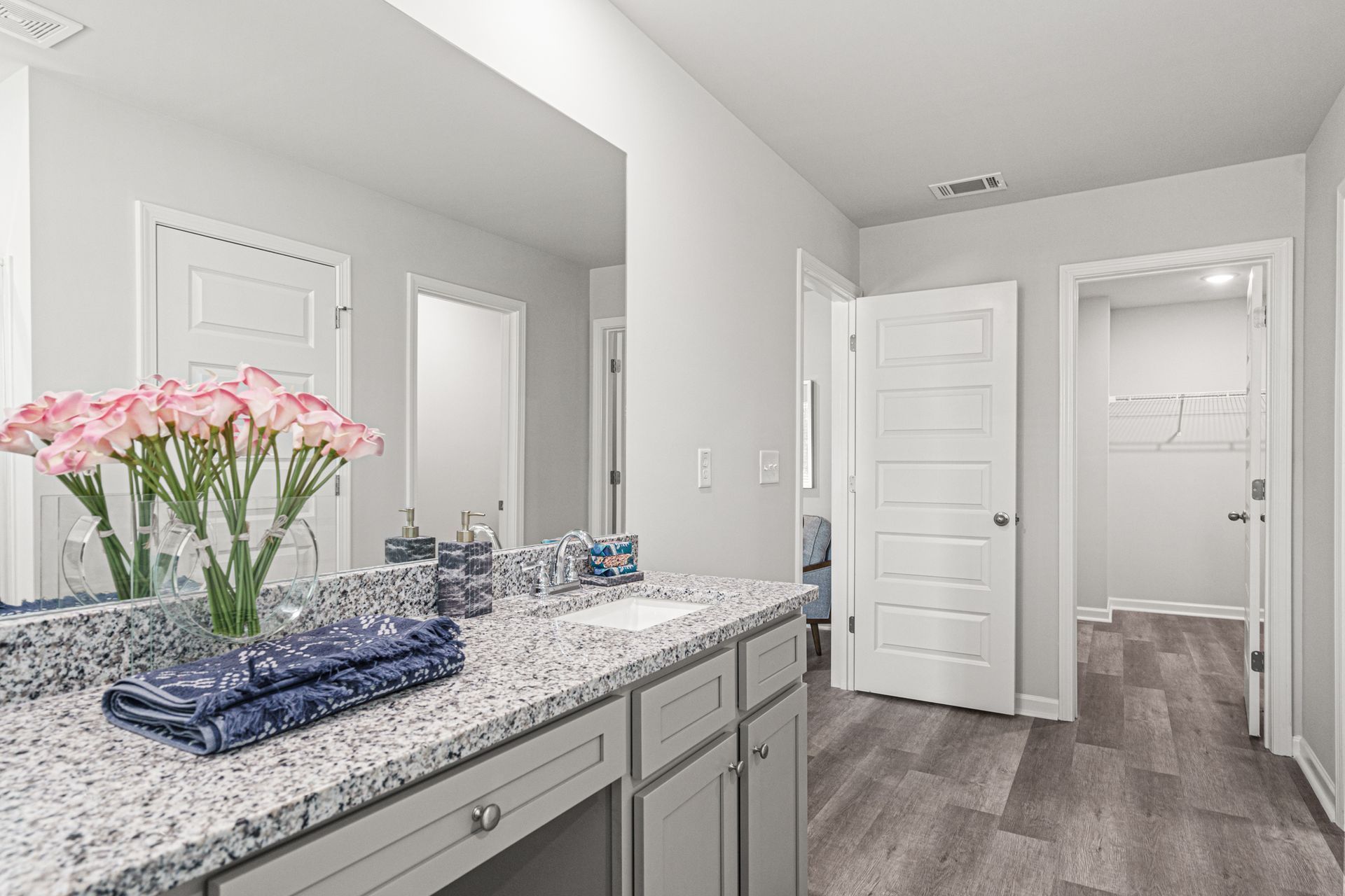 A bathroom with a sink , mirror and flowers on the counter.