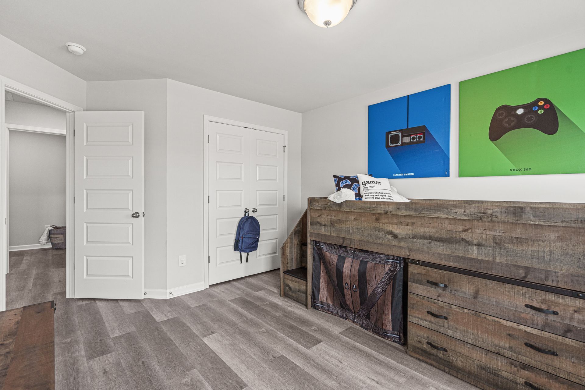 A bedroom with a bunk bed , dresser , and paintings on the wall.