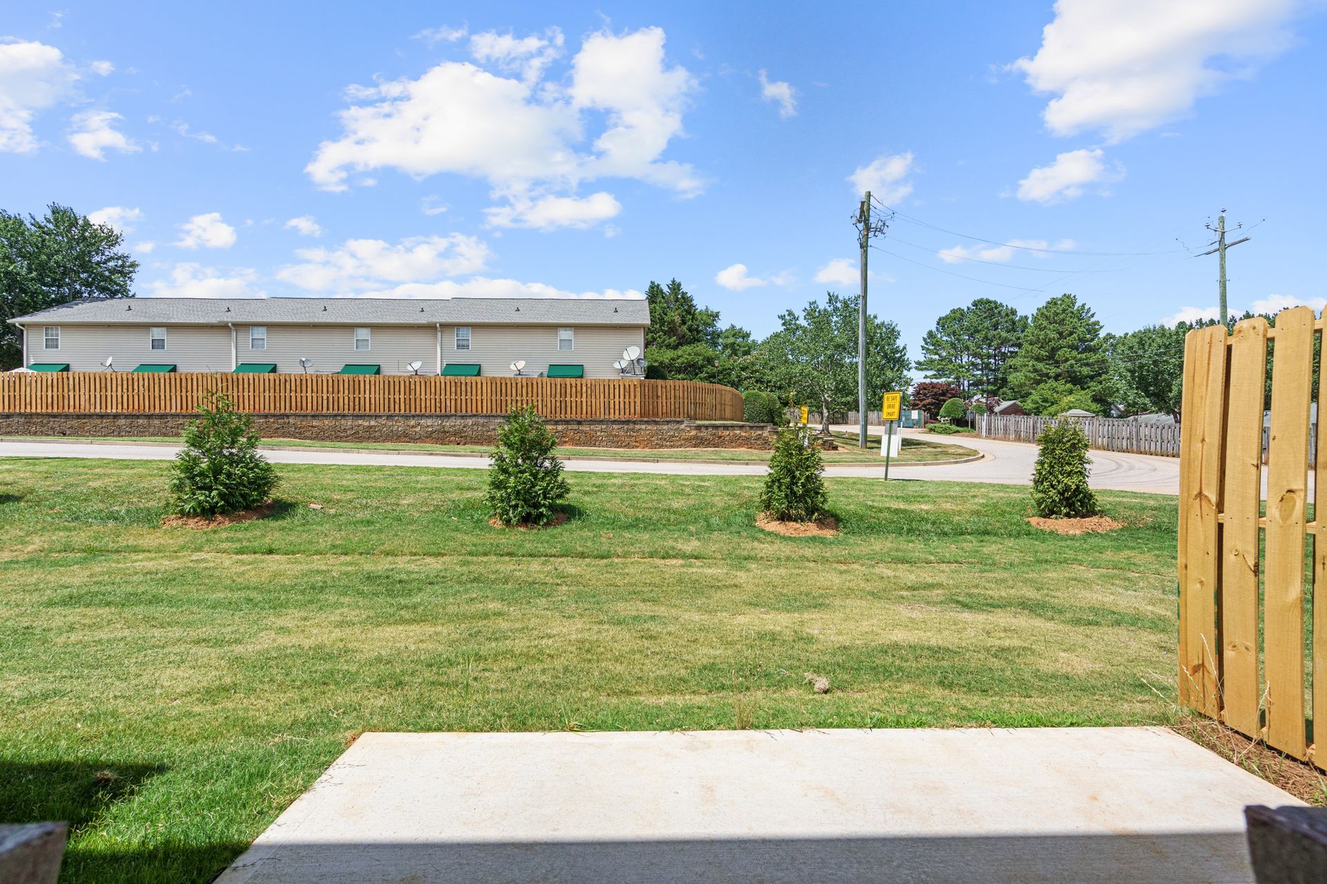 A large lawn with a wooden fence and a building in the background.