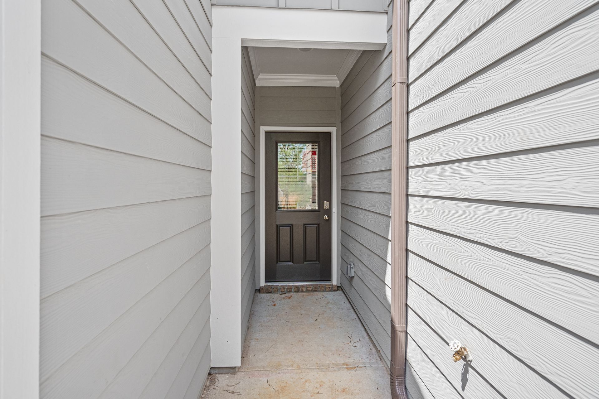 There is a door in the middle of a hallway between two houses.