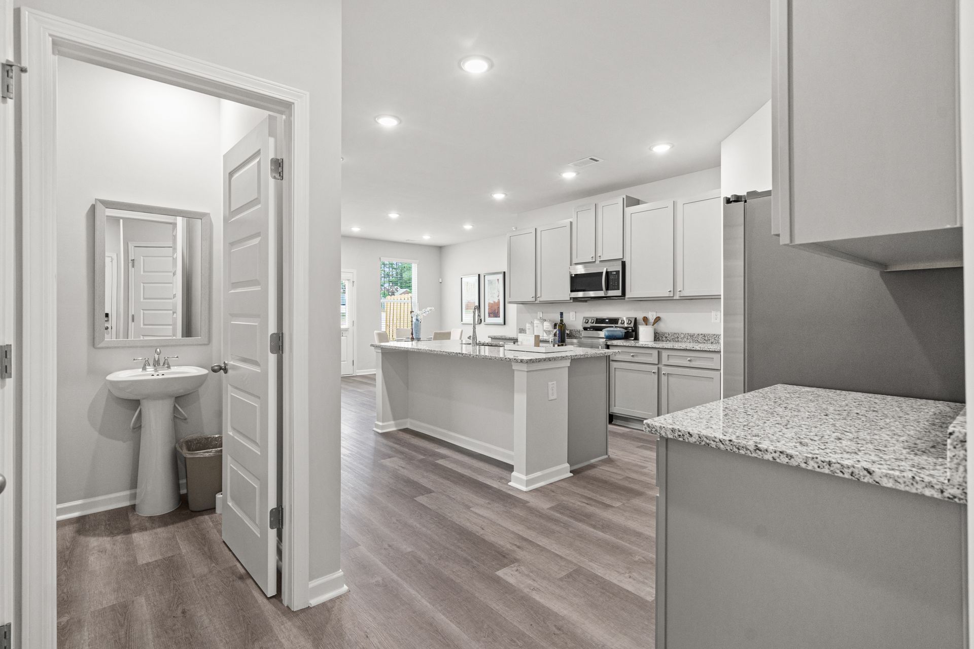 A kitchen with white cabinets , granite counter tops , stainless steel appliances and a sink.