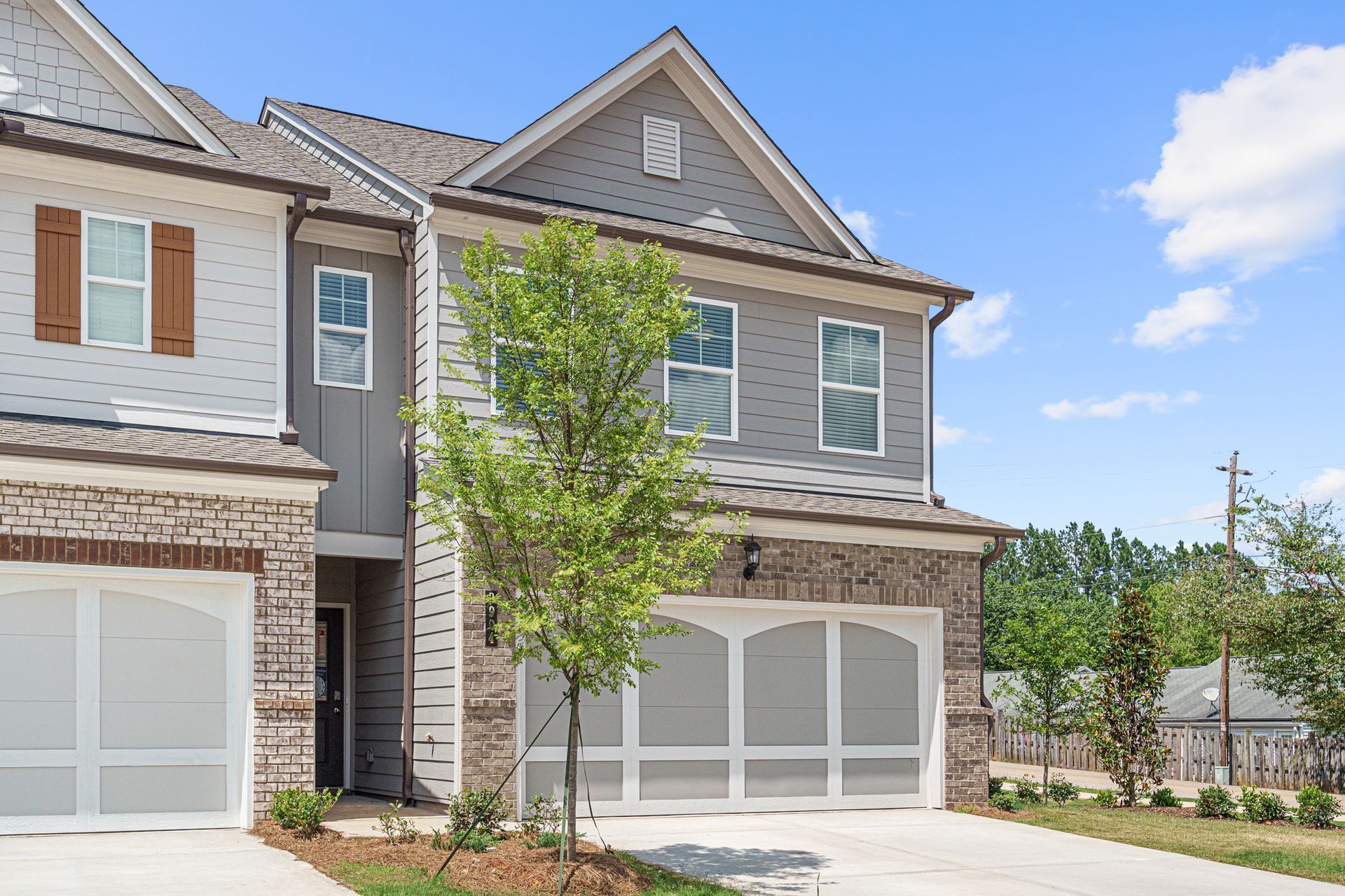 A large house with two garages and a tree in front of it.