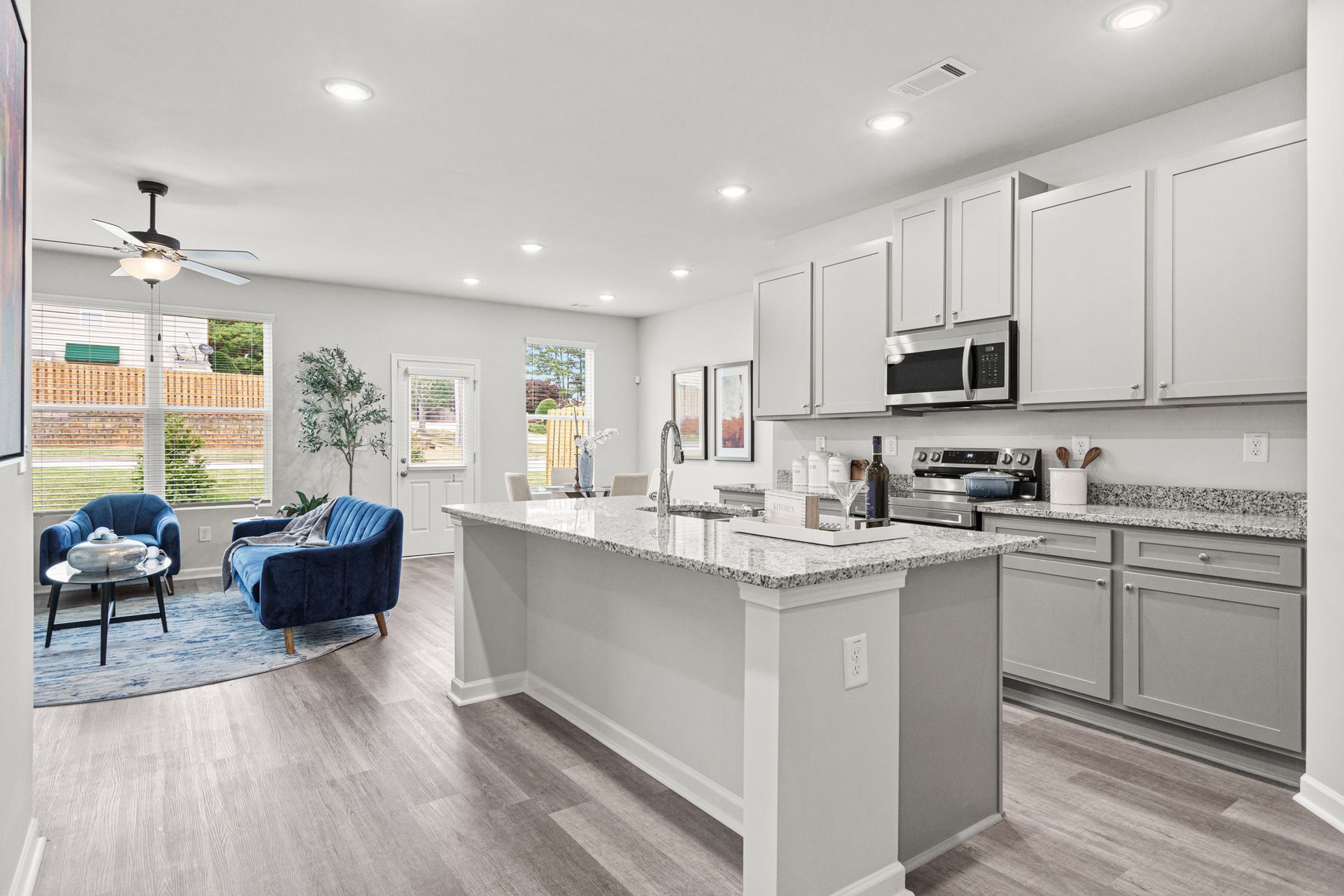 A kitchen with white cabinets and granite counter tops in a model home.