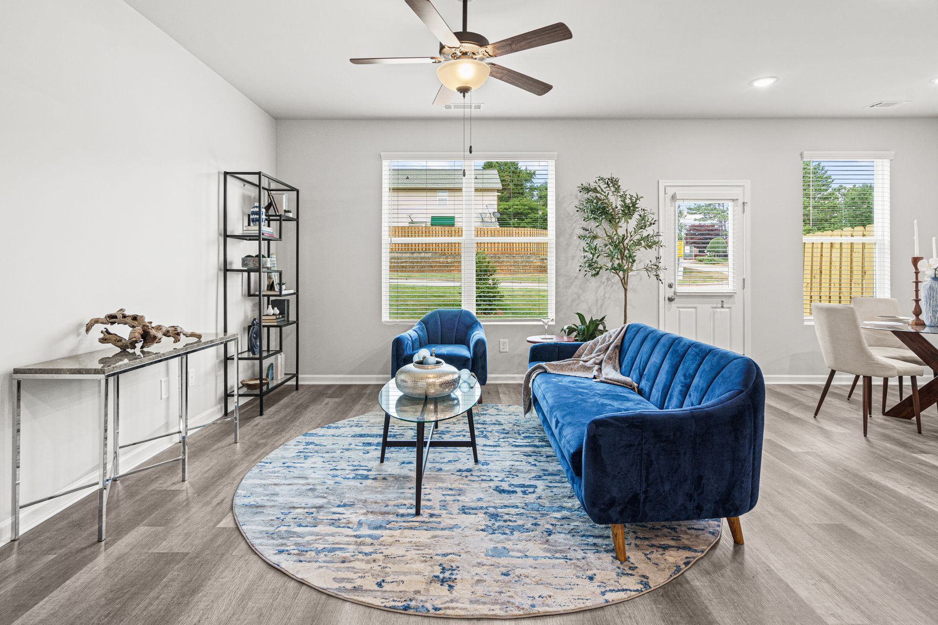 A living room with a blue couch and a ceiling fan.