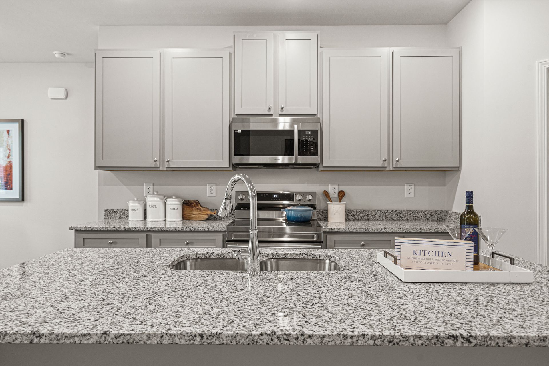 A kitchen with granite counter tops , stainless steel appliances , and white cabinets.