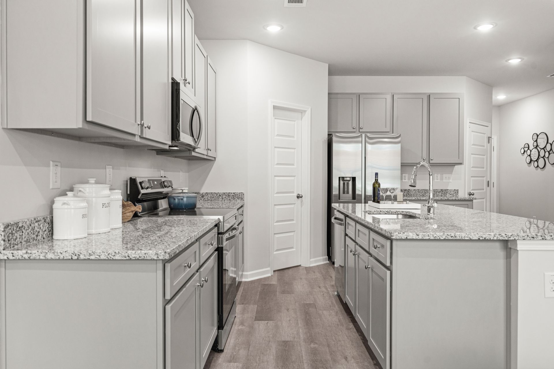 A kitchen with white cabinets , granite counter tops , stainless steel appliances and a large island.