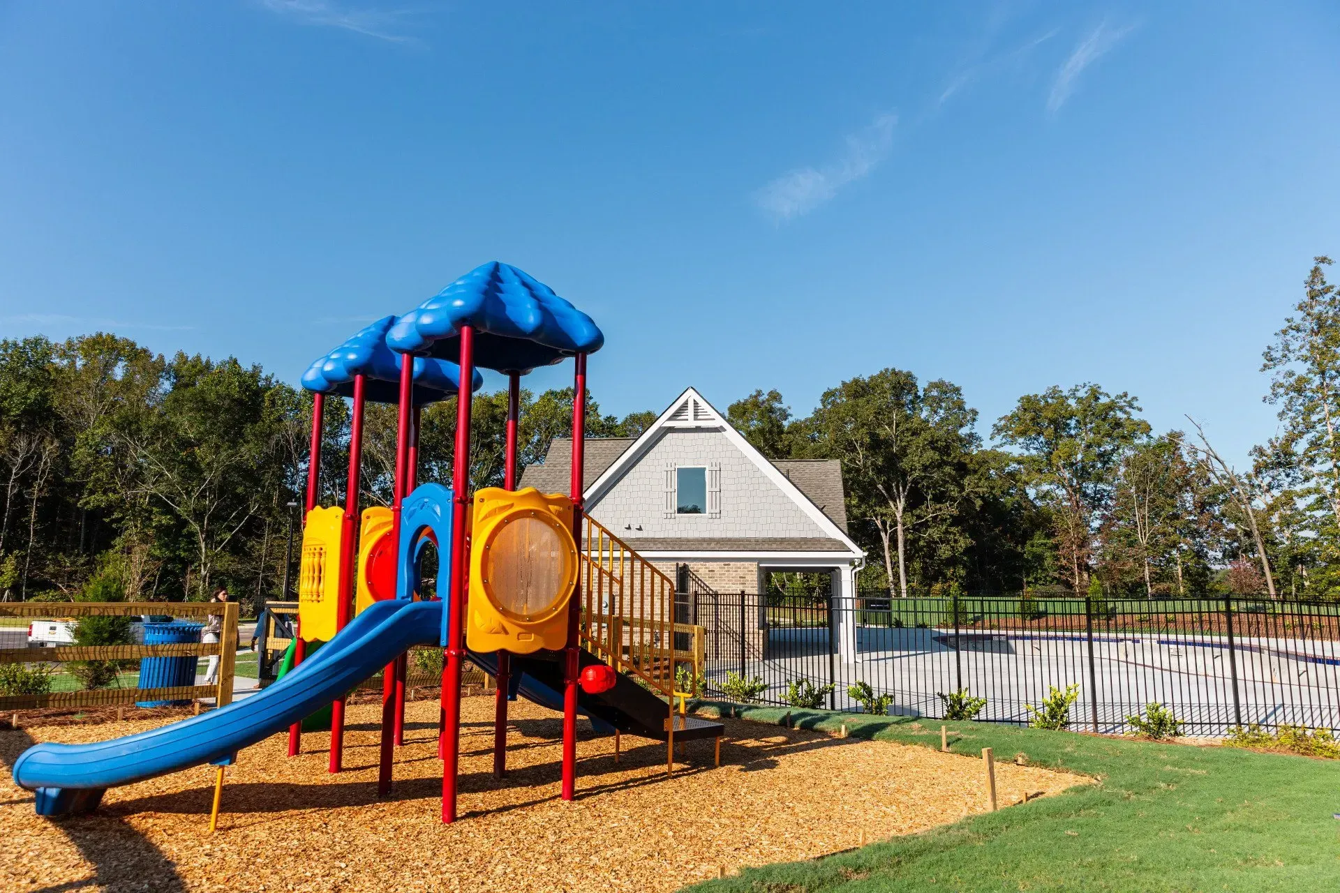 A colorful playground with a slide and stairs in front of a house.