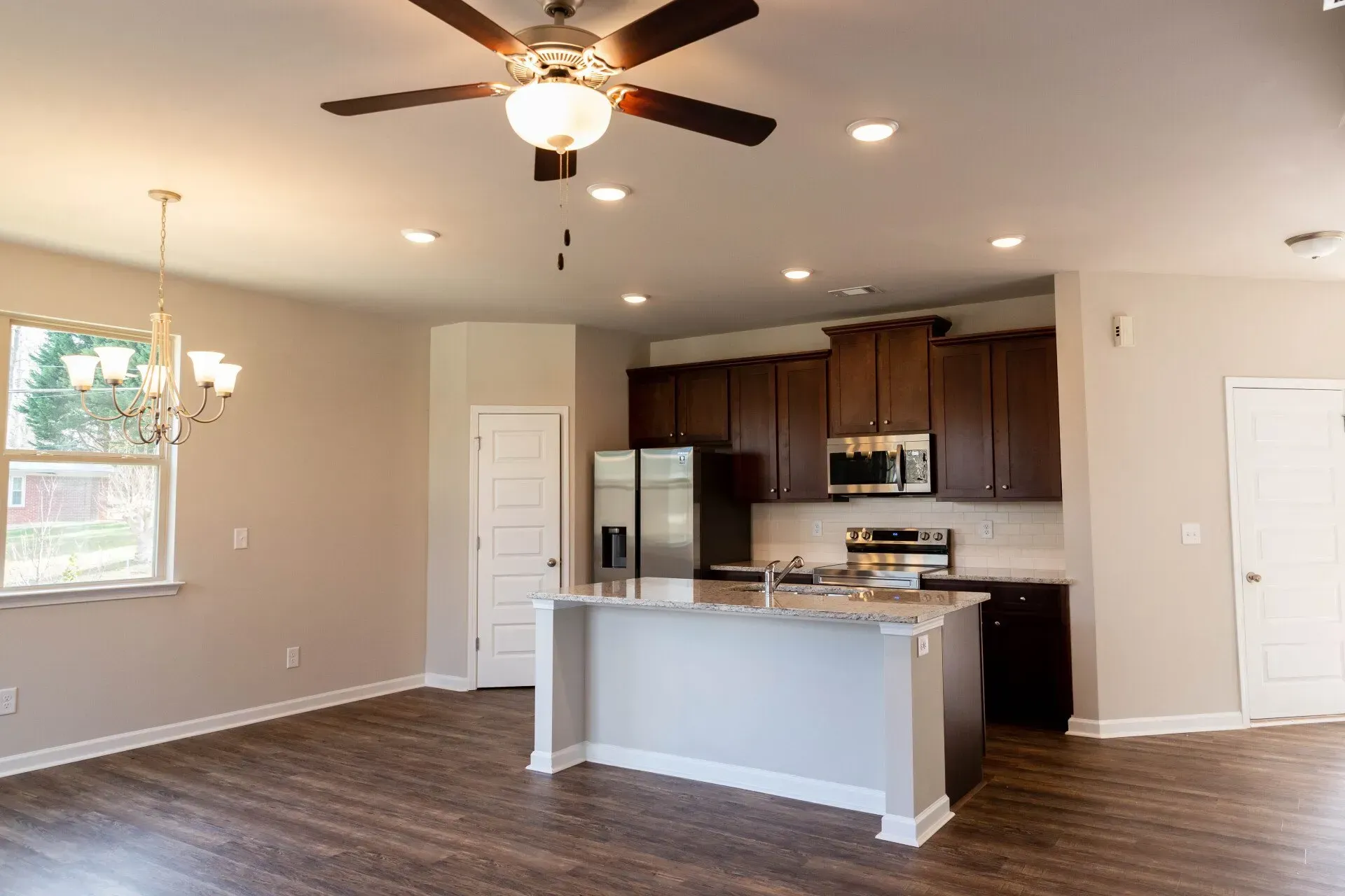 There is a ceiling fan in the kitchen and a large island in the middle of the room.