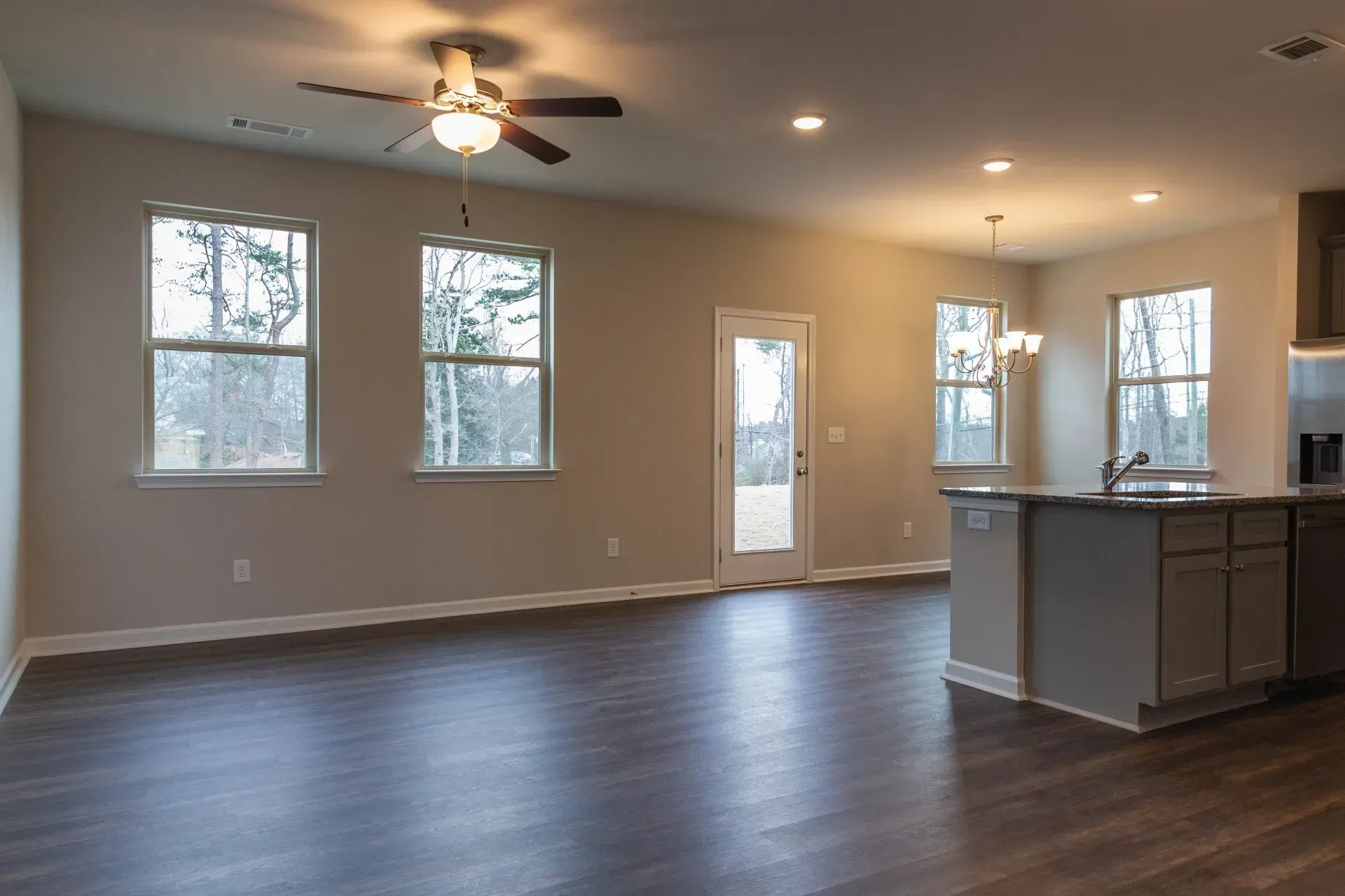 An empty living room with hardwood floors and a ceiling fan.