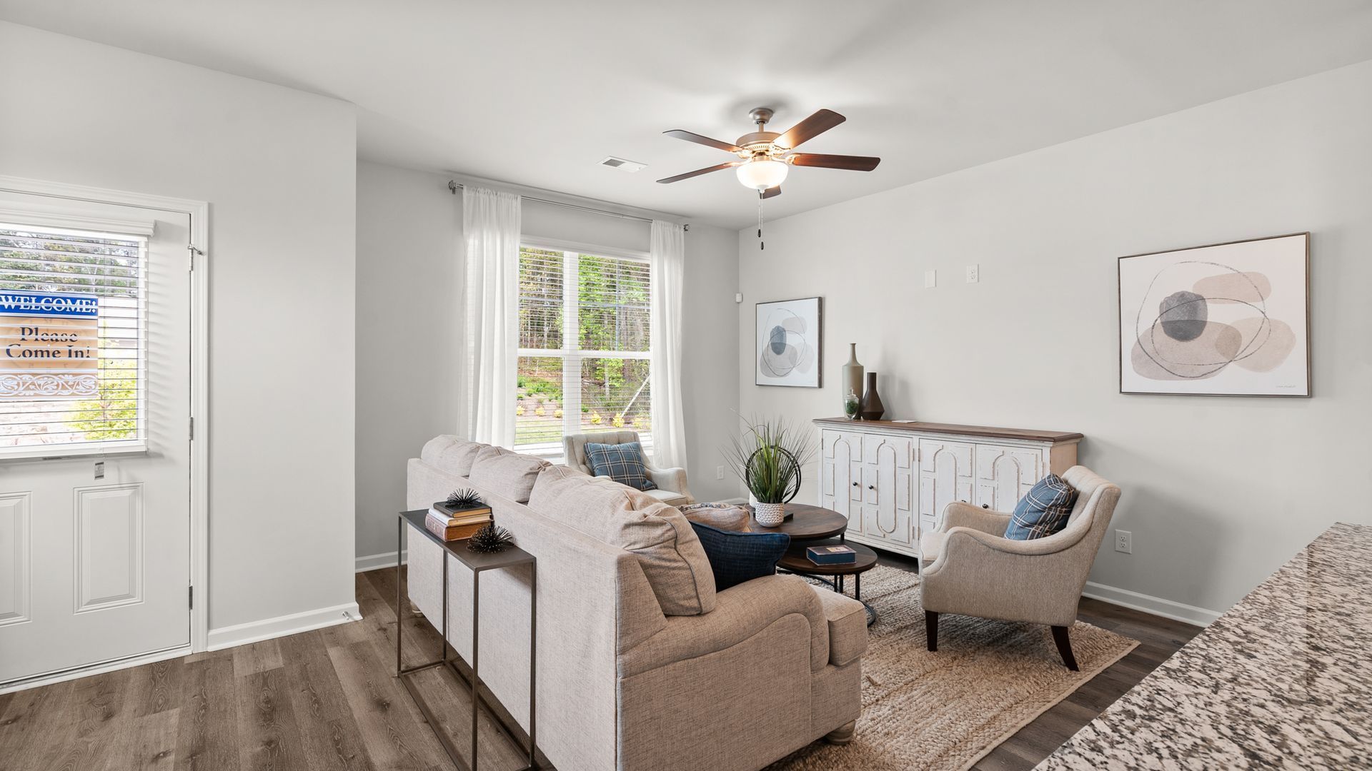 A living room with a couch , chairs , and a ceiling fan.