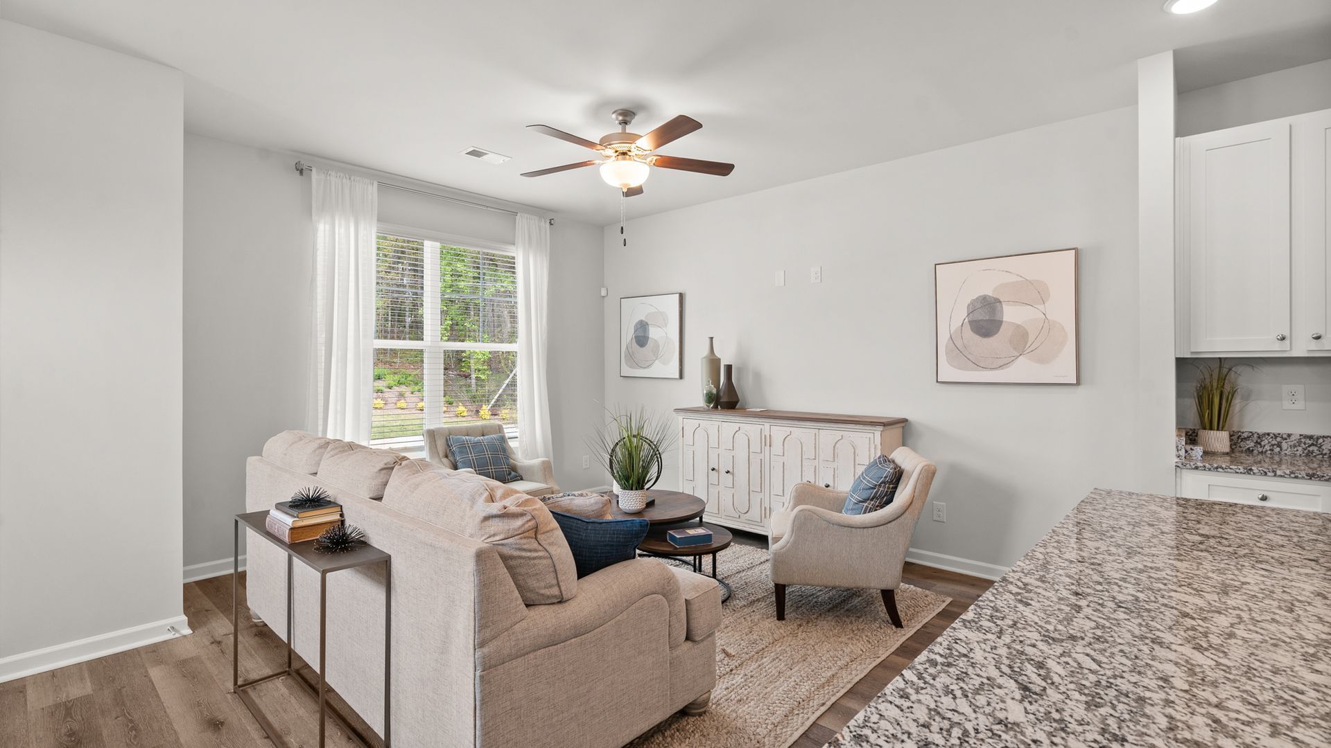 A living room with a couch , chairs , and a ceiling fan.