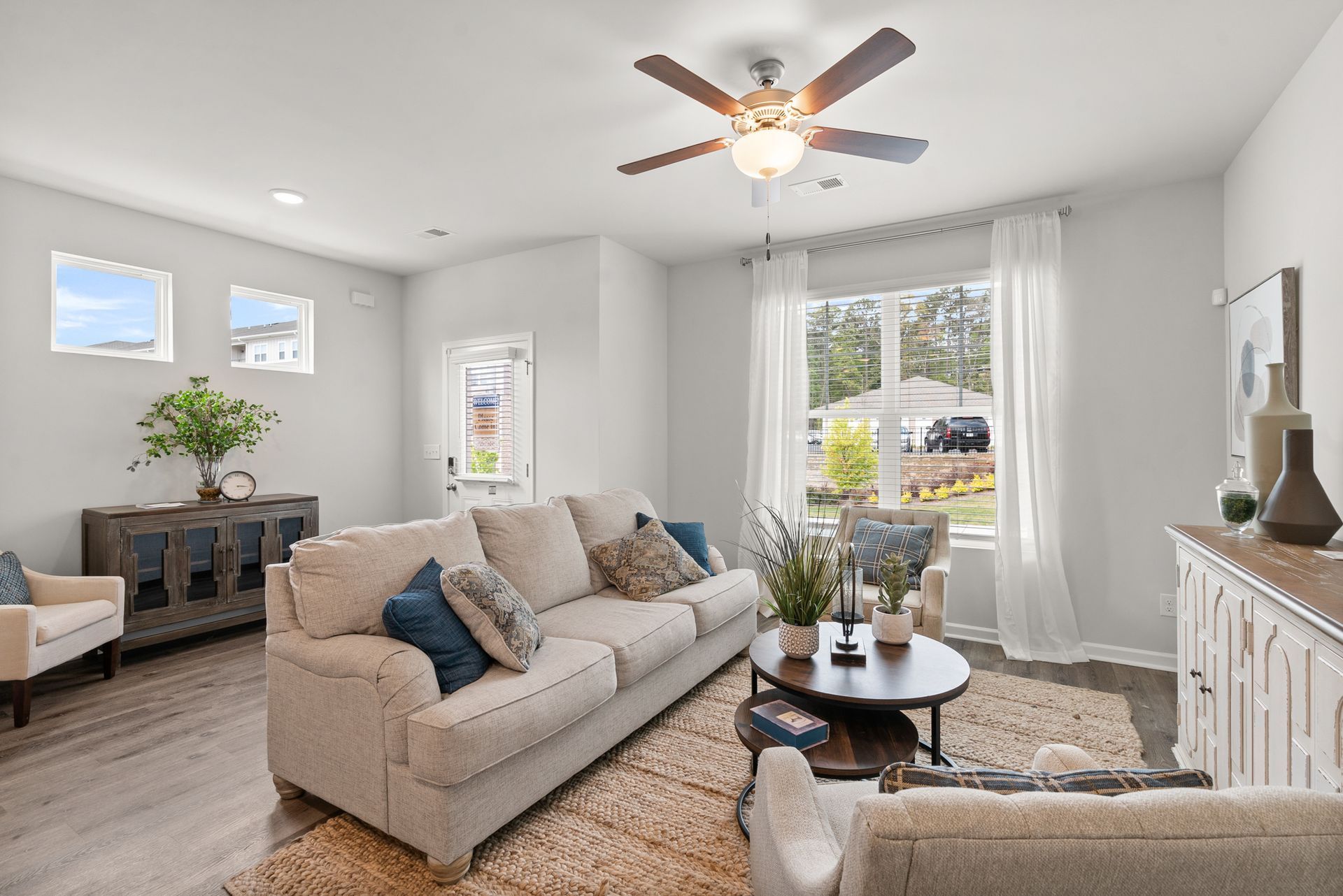 A living room with a couch , chairs , and a ceiling fan.