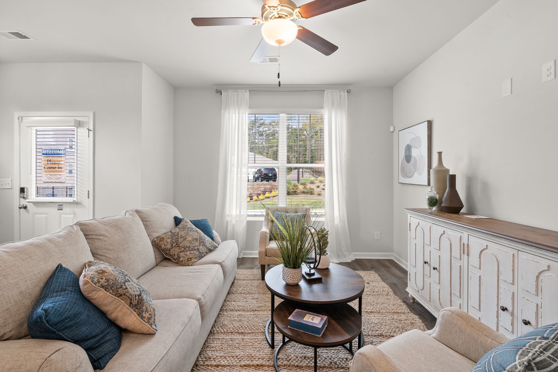 A living room with a couch , chair , coffee table and ceiling fan.