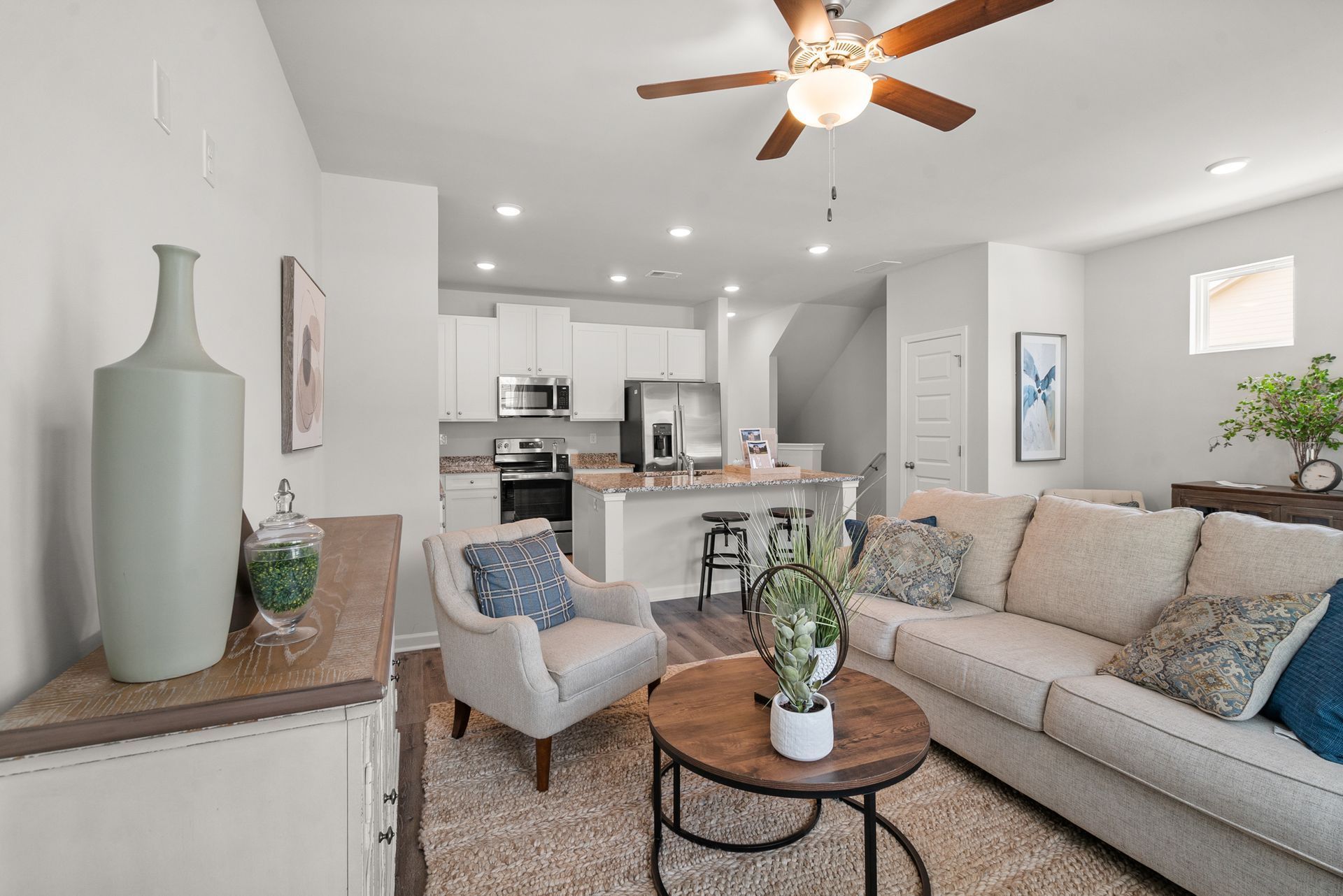 A living room with a couch , chair , coffee table and ceiling fan.