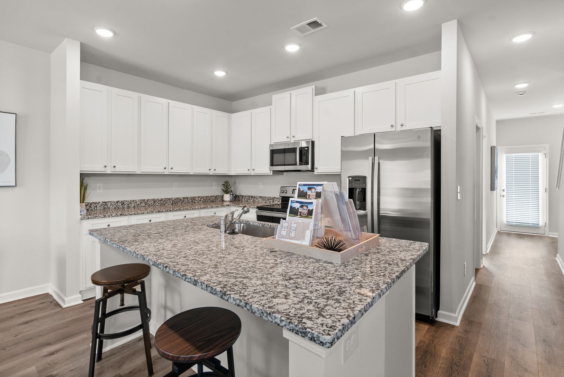 A kitchen with granite counter tops , stainless steel appliances , and white cabinets.