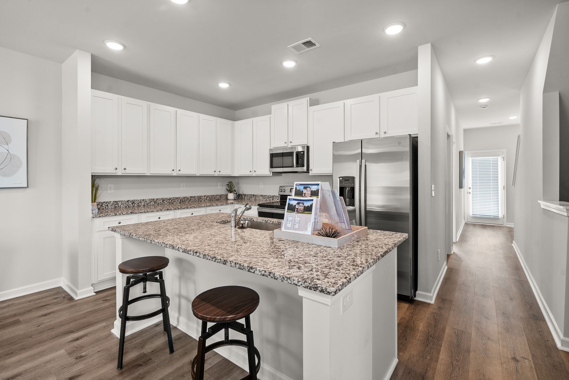 A kitchen with granite counter tops , stainless steel appliances , and white cabinets.